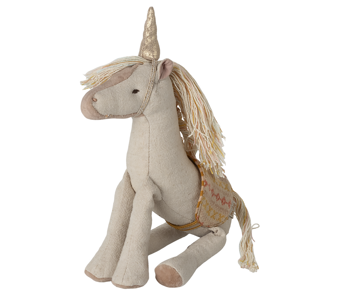 Cream colored fabric unicorn plush toy with golden horn and mane sitting on white surface