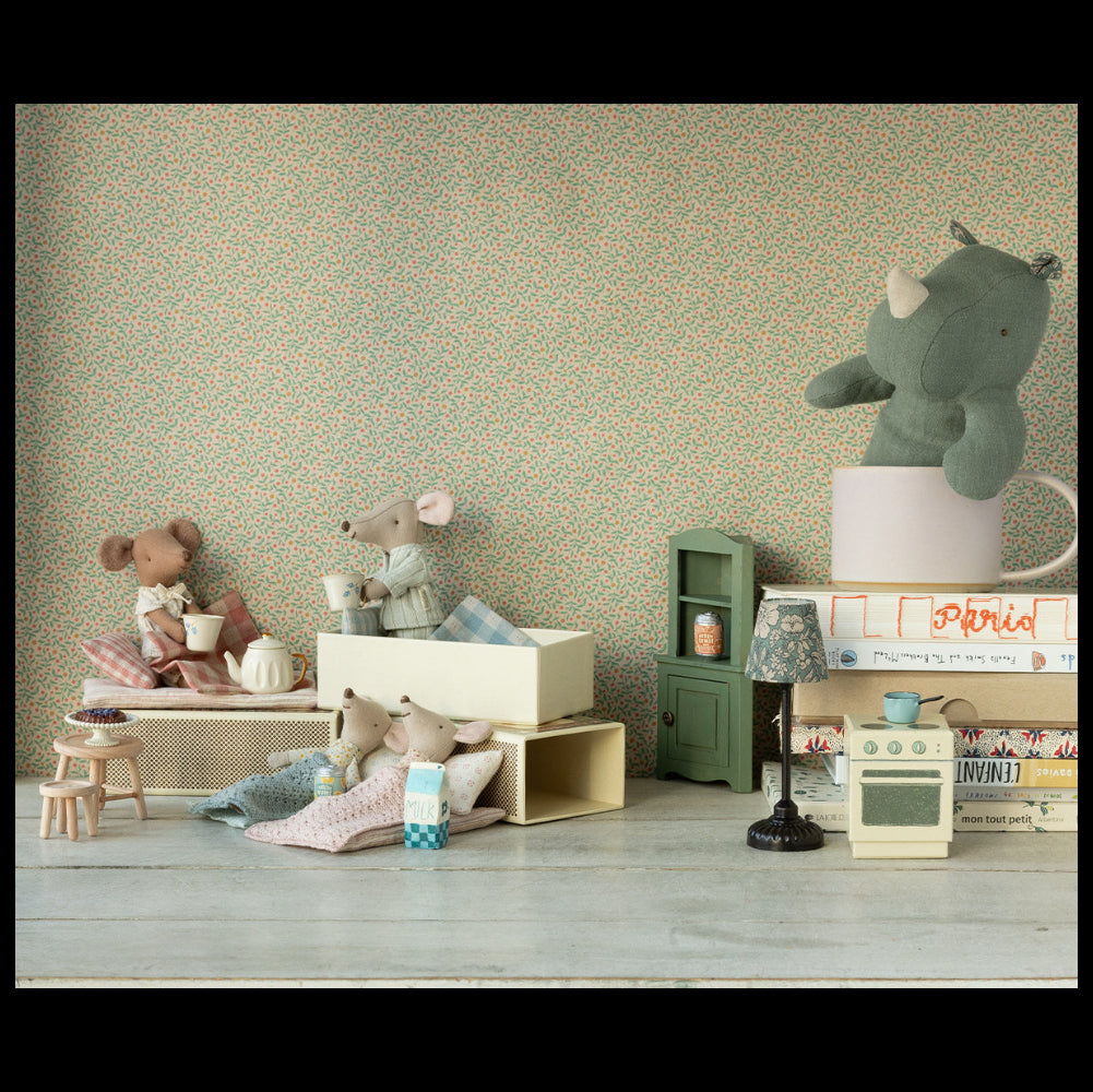 Maileg big sister mouse toy in striped pajamas lying in white matchbox bed with other toys