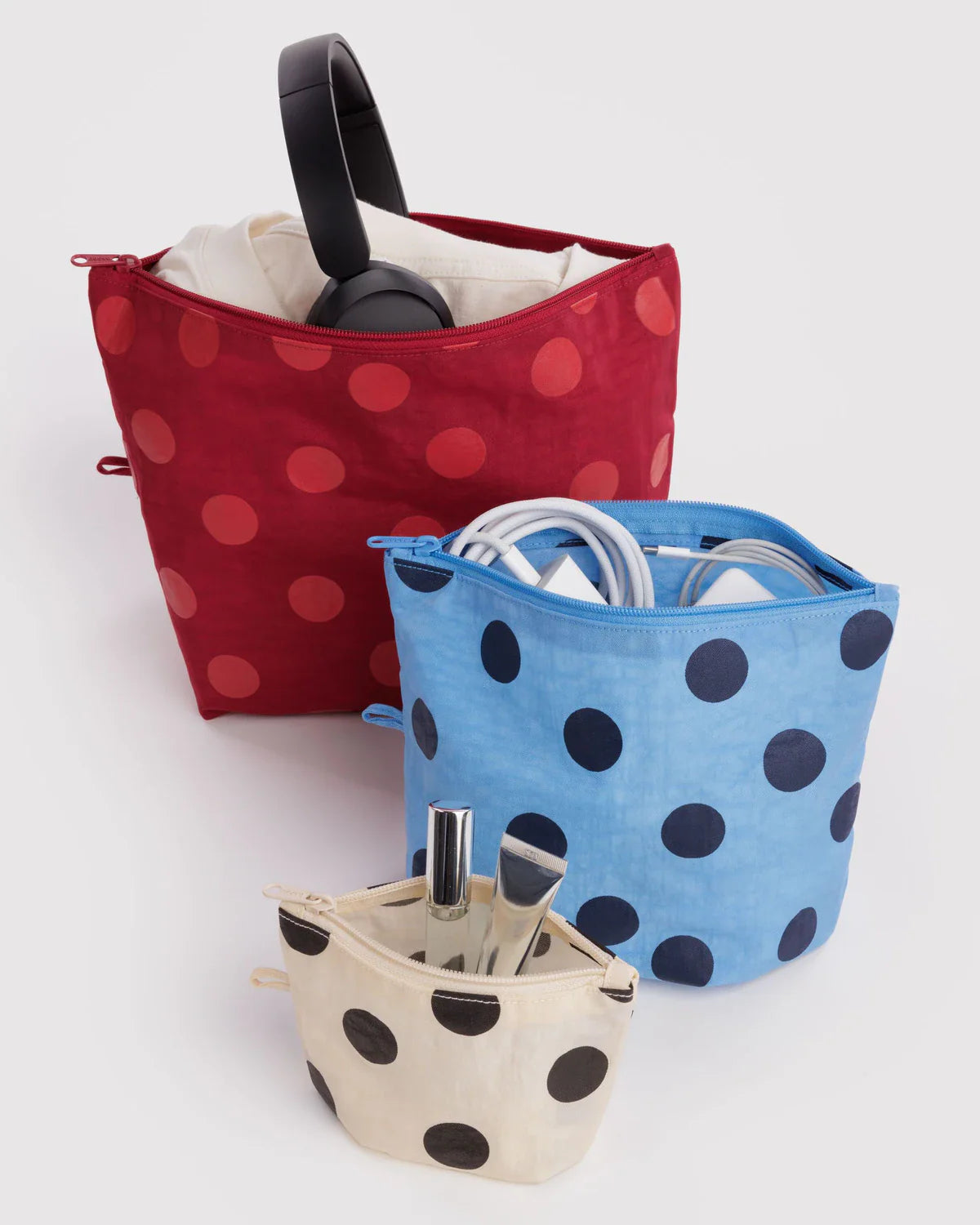 Three polka dot zip pouches in red, blue, and cream sizes with accessories inside