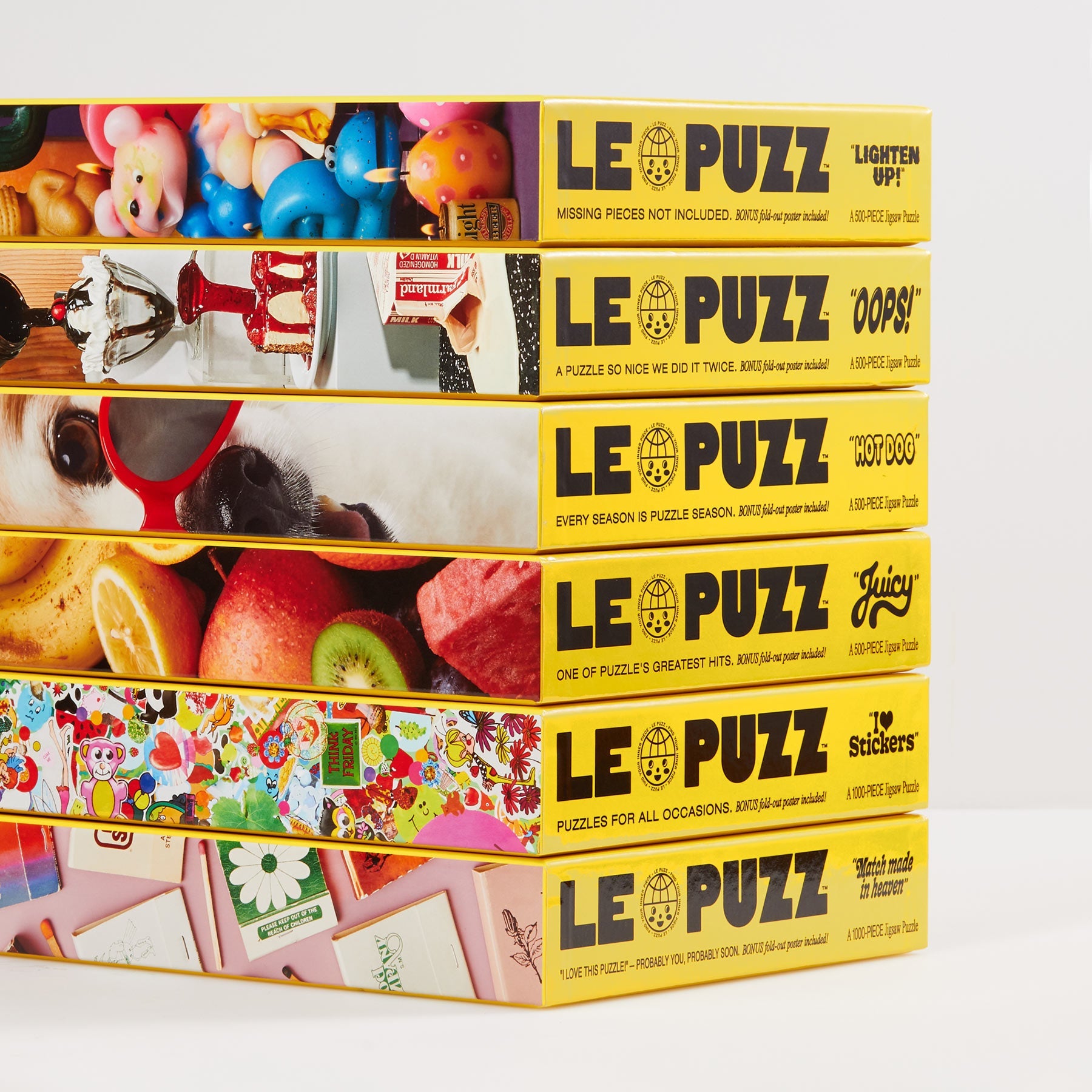 Stack of six Le Puzz jigsaw puzzle boxes with yellow spines, Match Made in Heaven visible at bottom