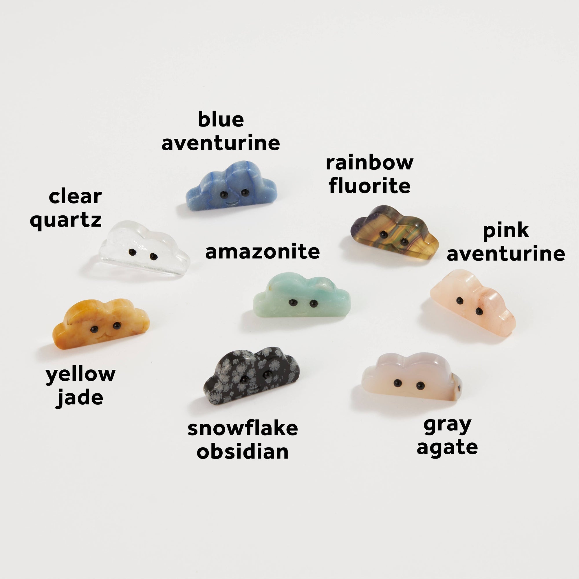 Eight crystal cloud-shaped figurines with cartoon eyes in various gemstone varieties on white background