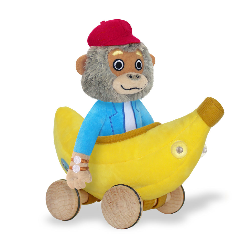 Yottoy plush gorilla toy wearing red cap and blue jacket riding yellow banana-shaped vehicle with wooden wheels
