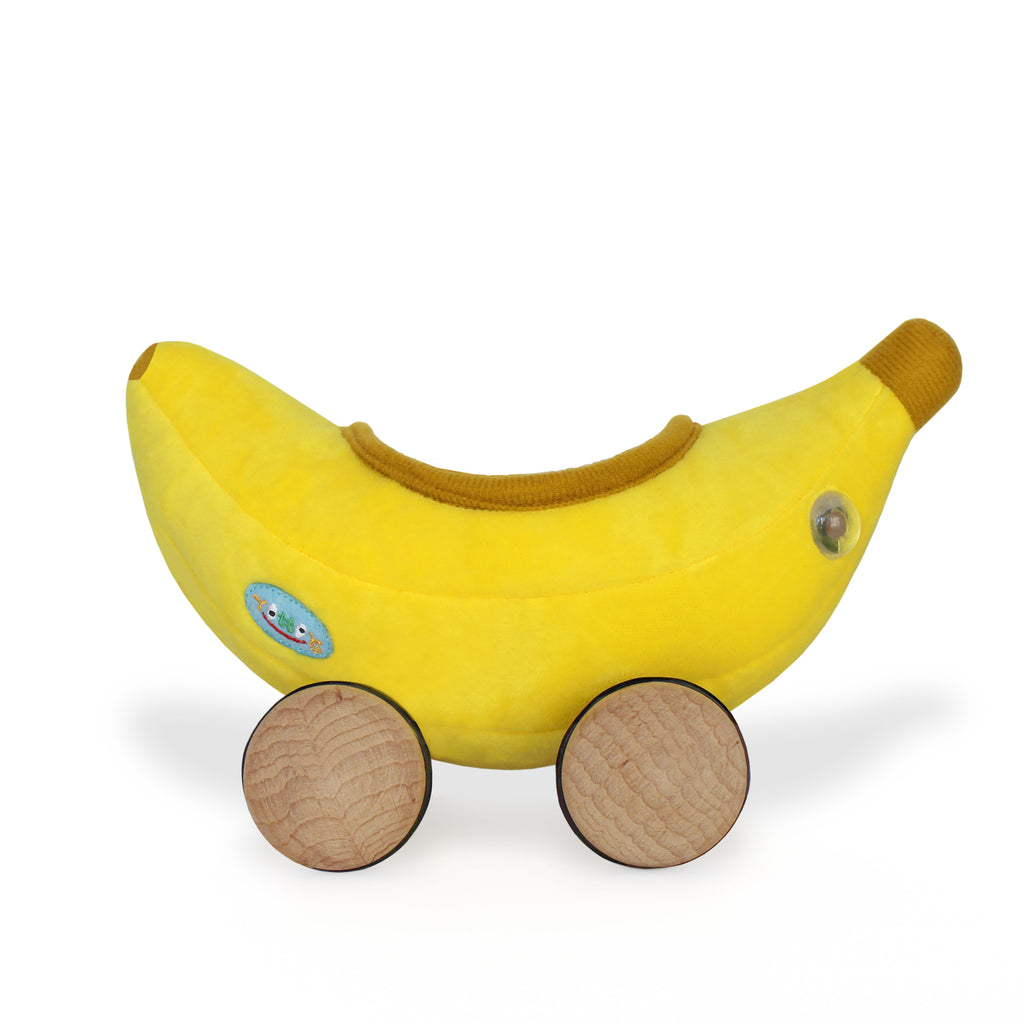 Yellow plush banana toy on two round wooden wheels, resembling a bananamobile vehicle