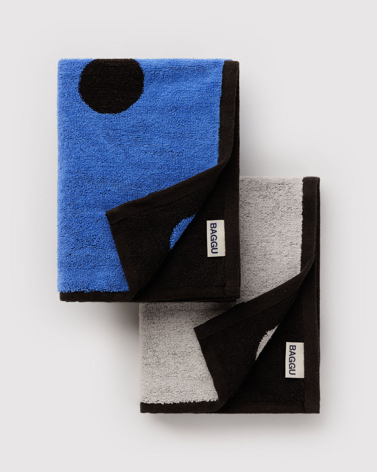 Two folded Baggu hand towels featuring bold polka dot patterns in blue-black and grey-black colorways