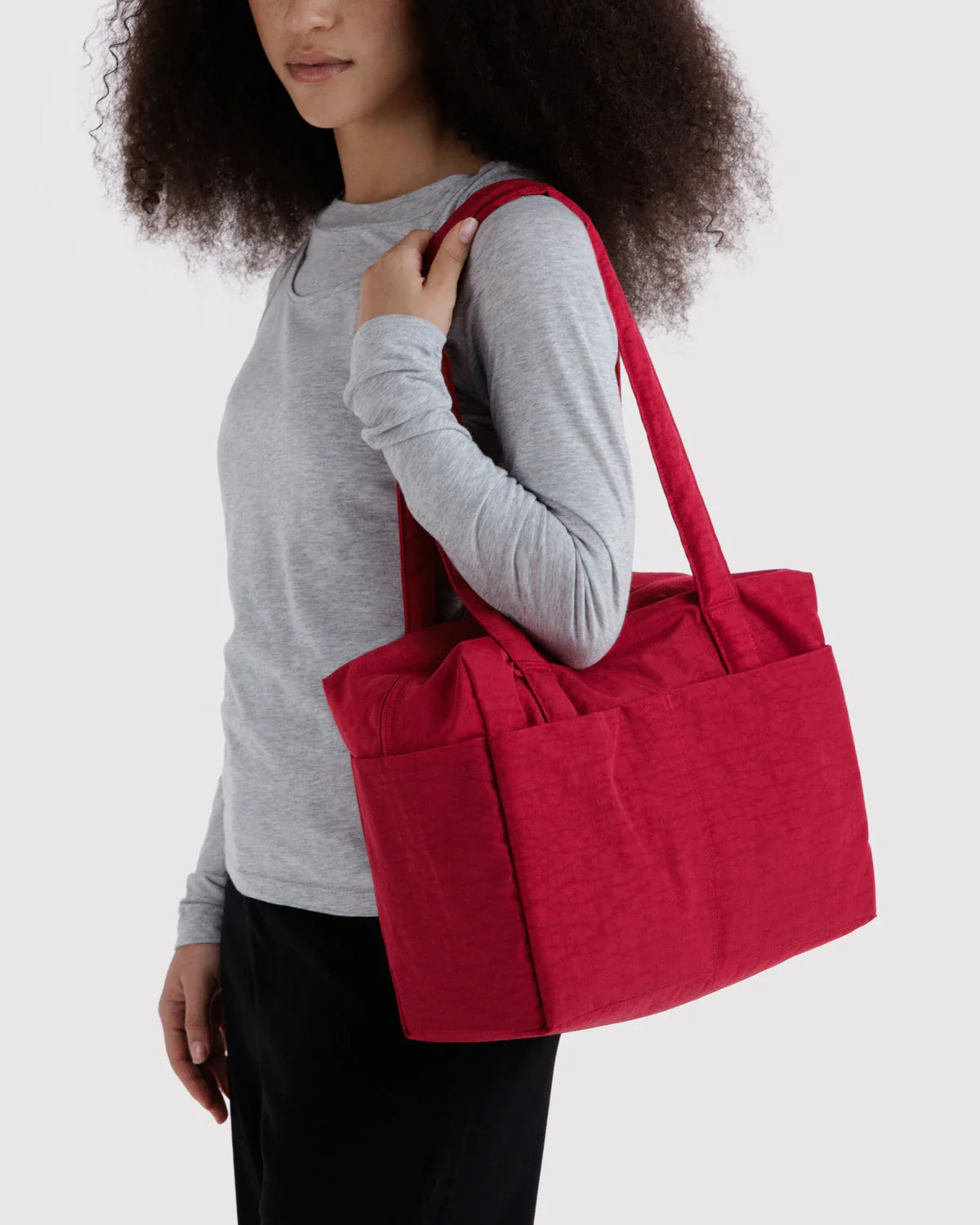 Model carrying large red Baggu Everyday Cloud Bag on shoulder against white background