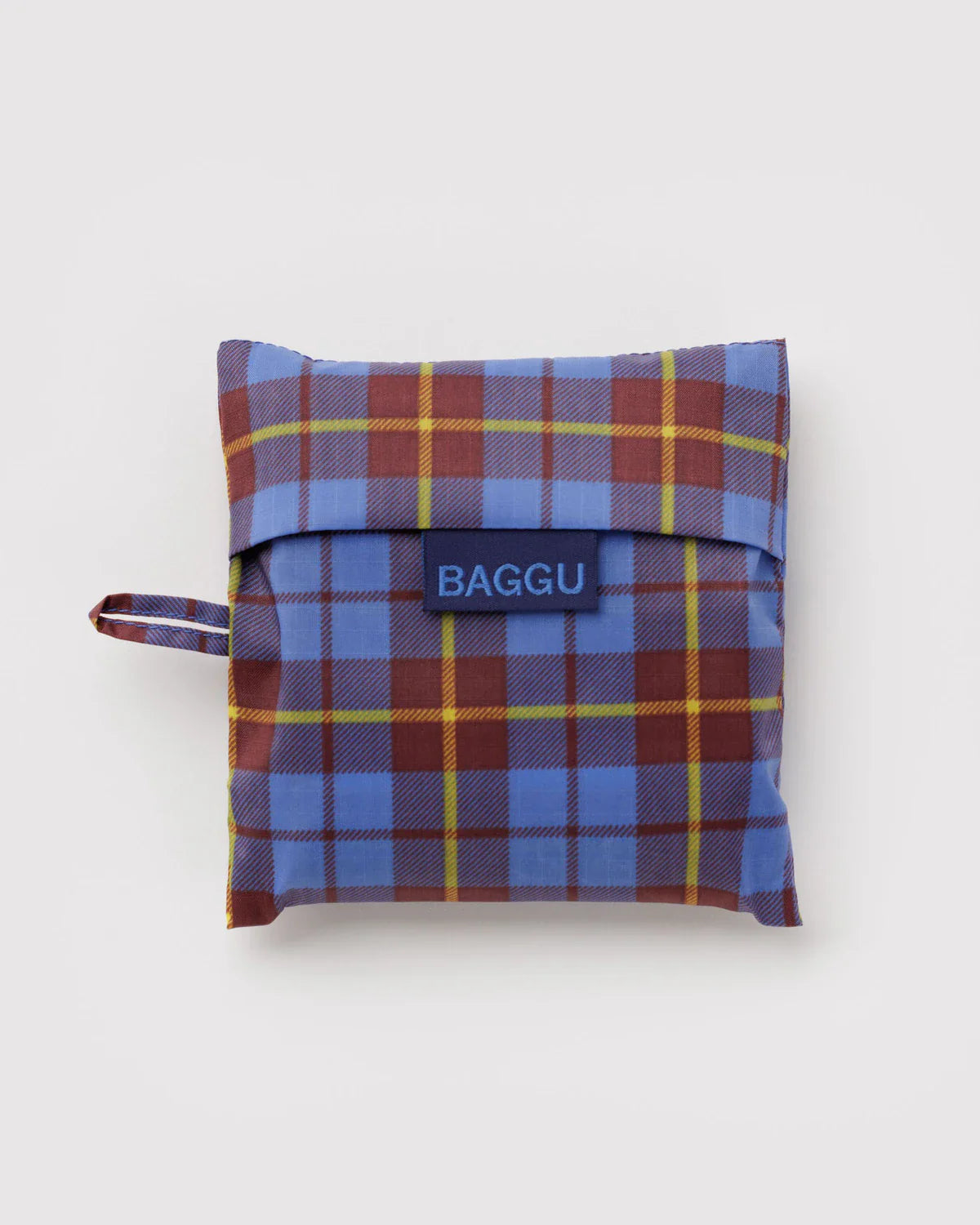 Baggu Standard reusable bag folded into blue, burgundy, and yellow tartan pouch