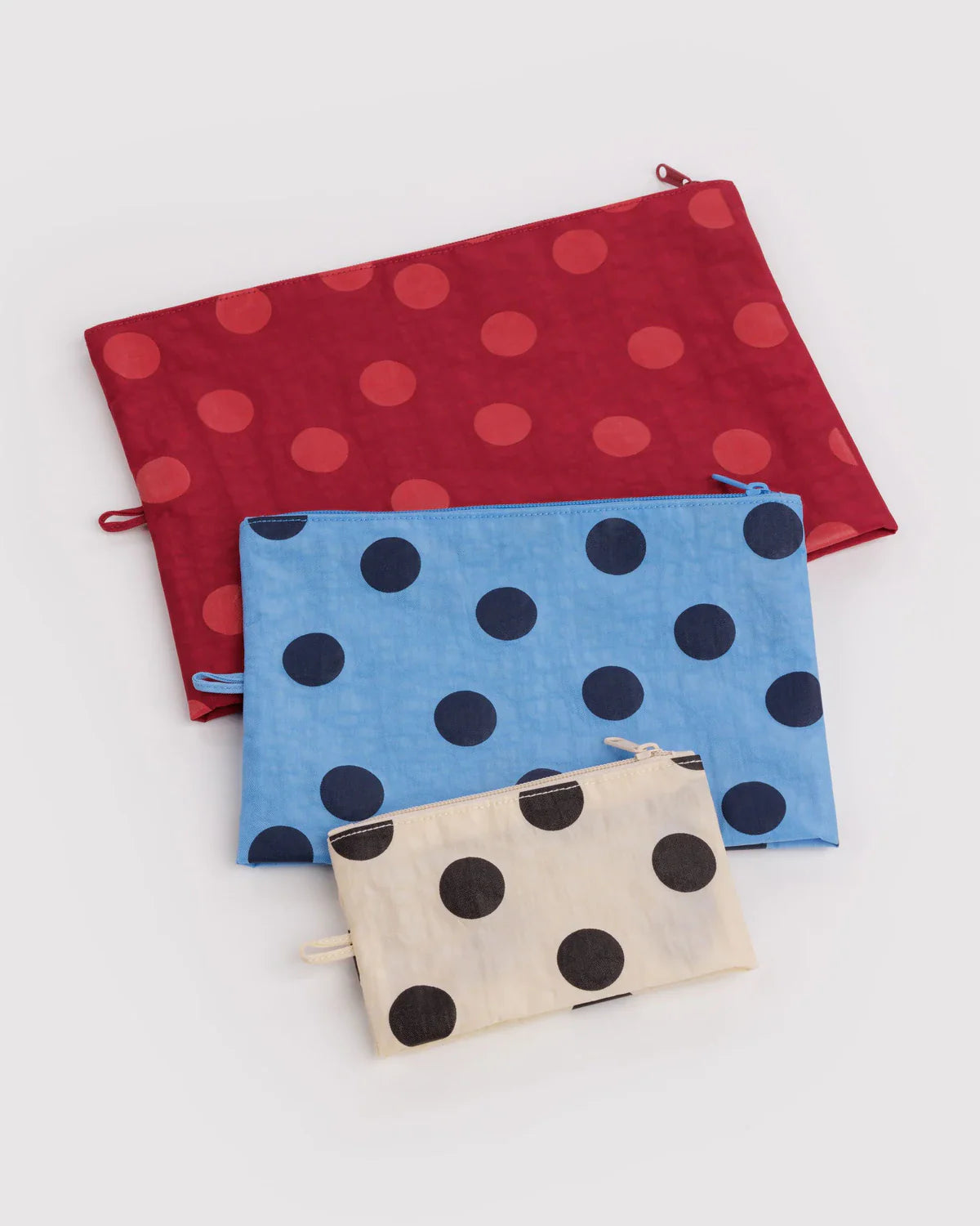 Three polka dot zip pouches in red, blue, and cream arranged by size on white background