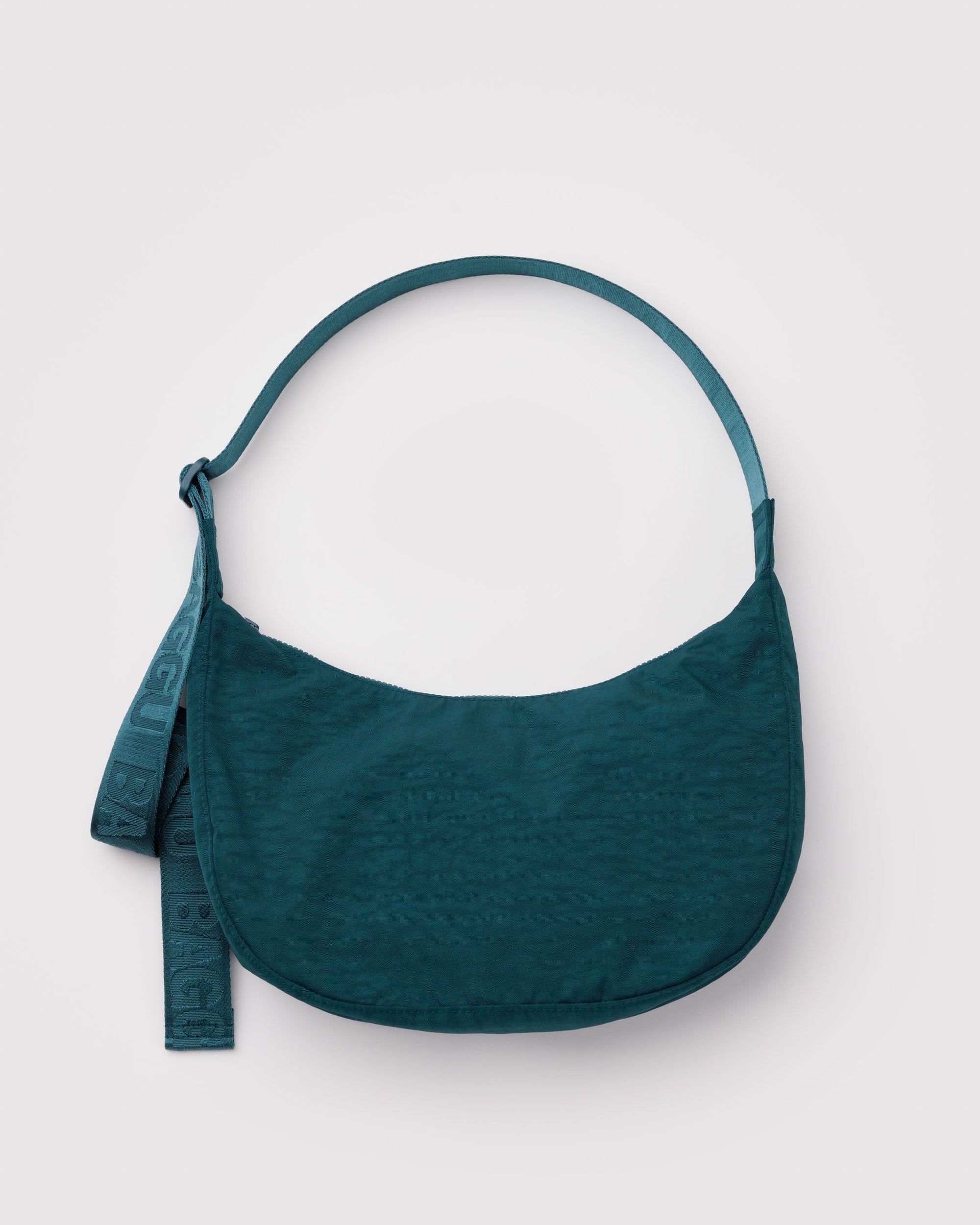 Baggu Medium Nylon Crescent Bag in deep teal with adjustable logo strap on white background
