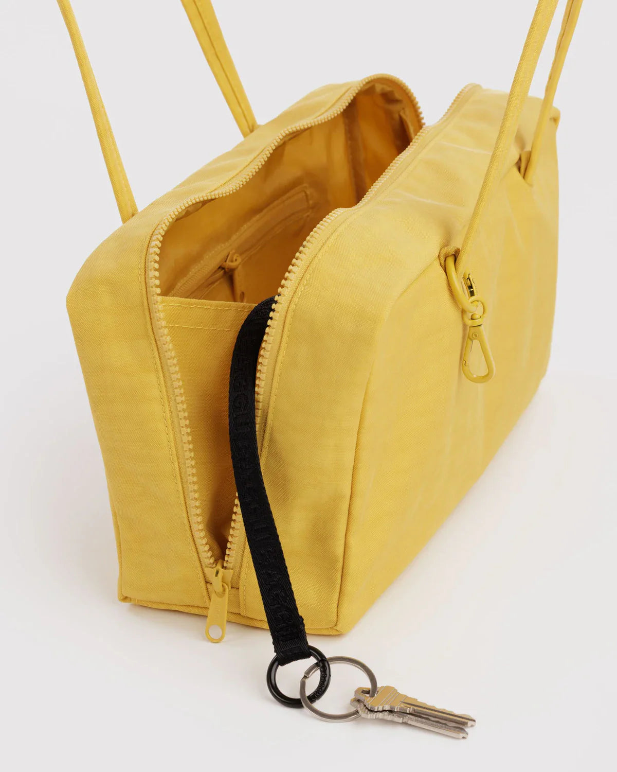 Open yellow Baggu Nylon Bowler bag showing interior compartment, zipper, and attached key lanyard