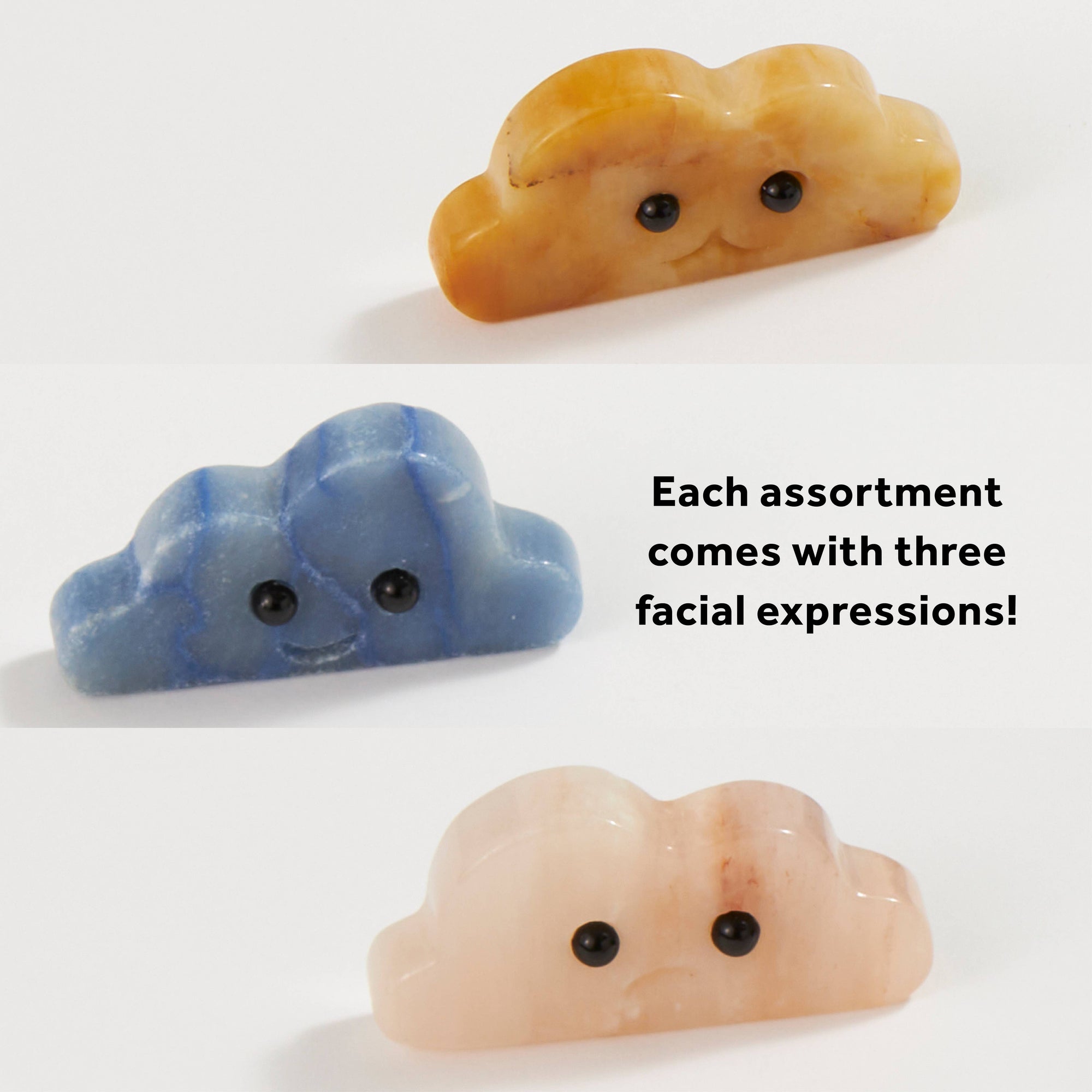 Three carved stone cloud figurines with cute faces in yellow, blue, and pink colors