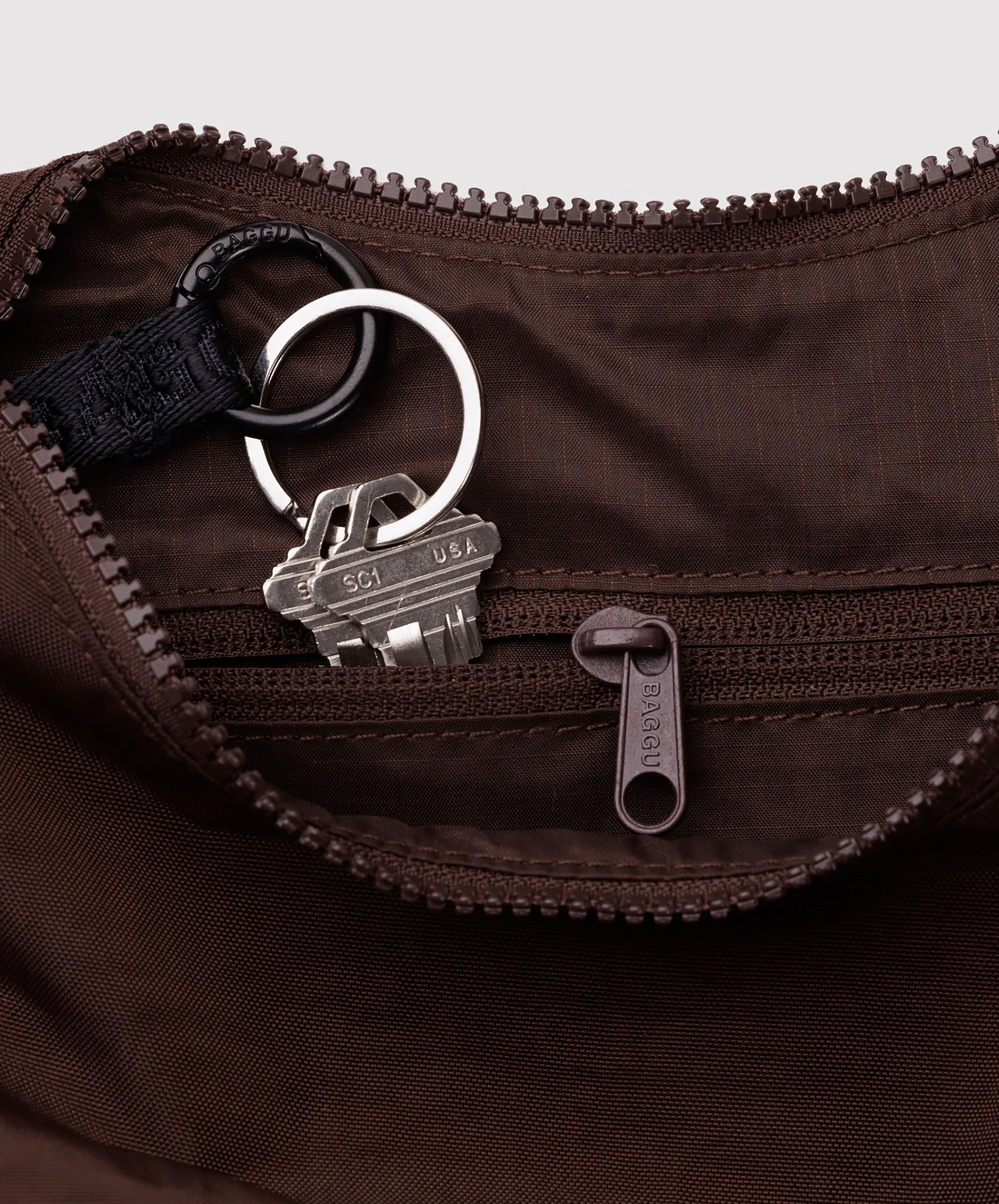 Interior view of Baggu Small Nylon Crescent Bag in coffee brown showing keys on interior clip and zipper pocket