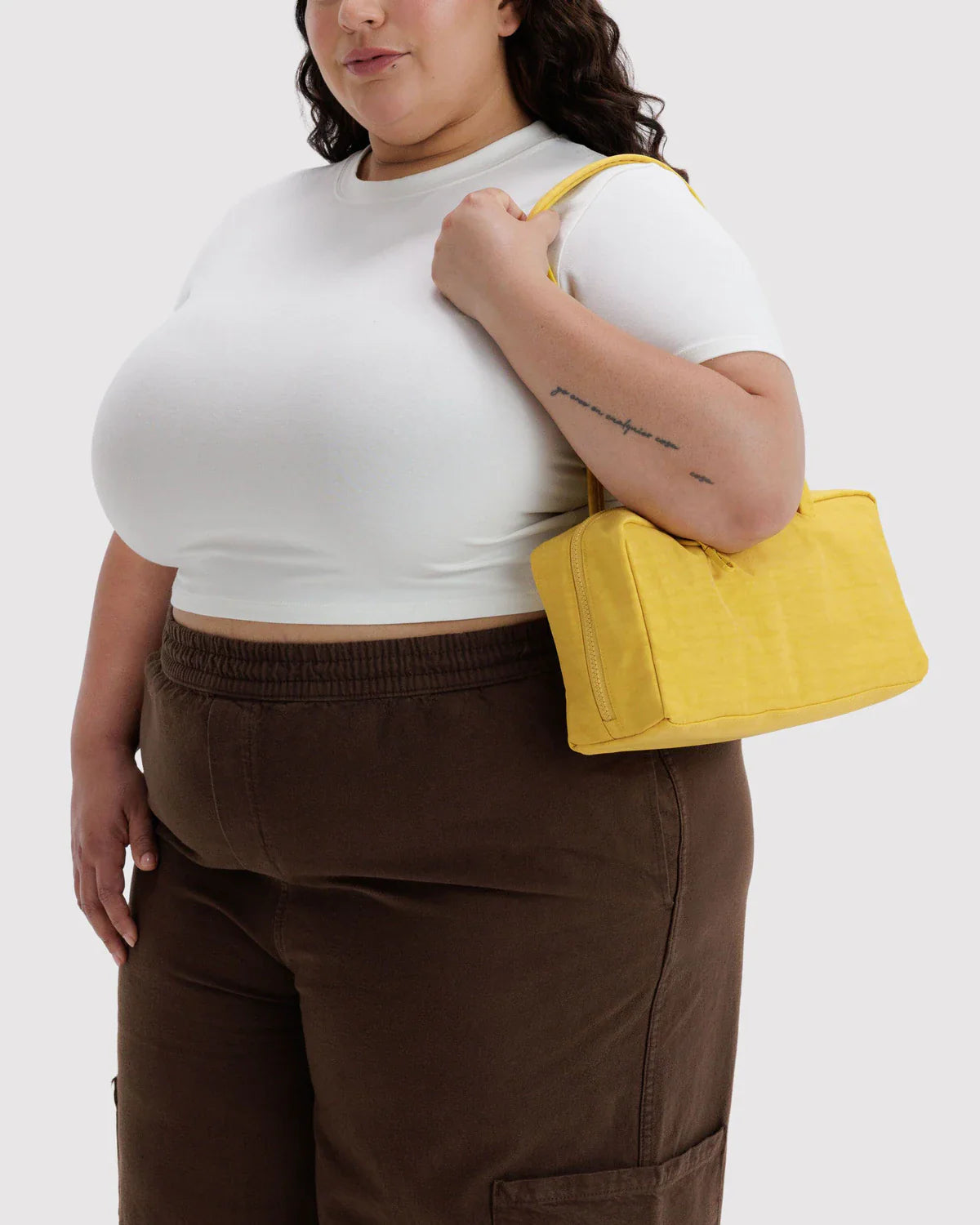 Model carrying yellow Baggu Nylon Bowler bag over shoulder wearing white crop top