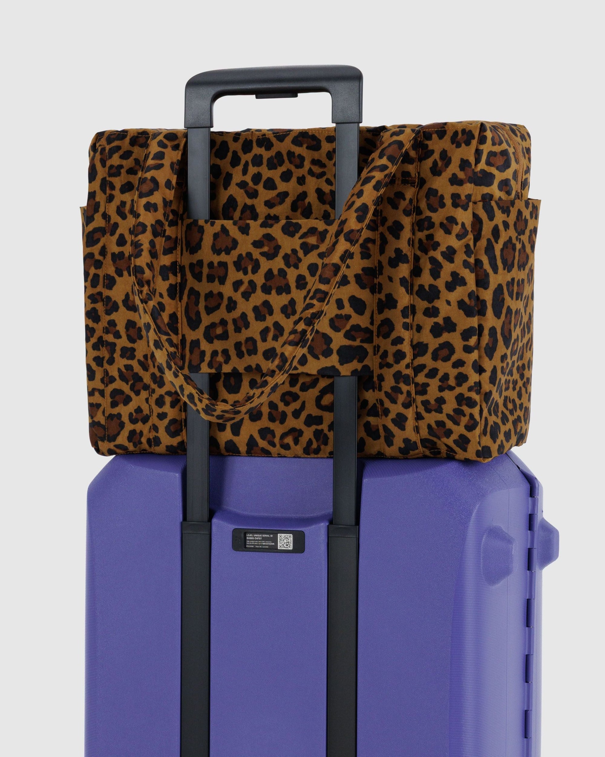Leopard print carry-on bag with laptop pocket attached to purple rolling suitcase