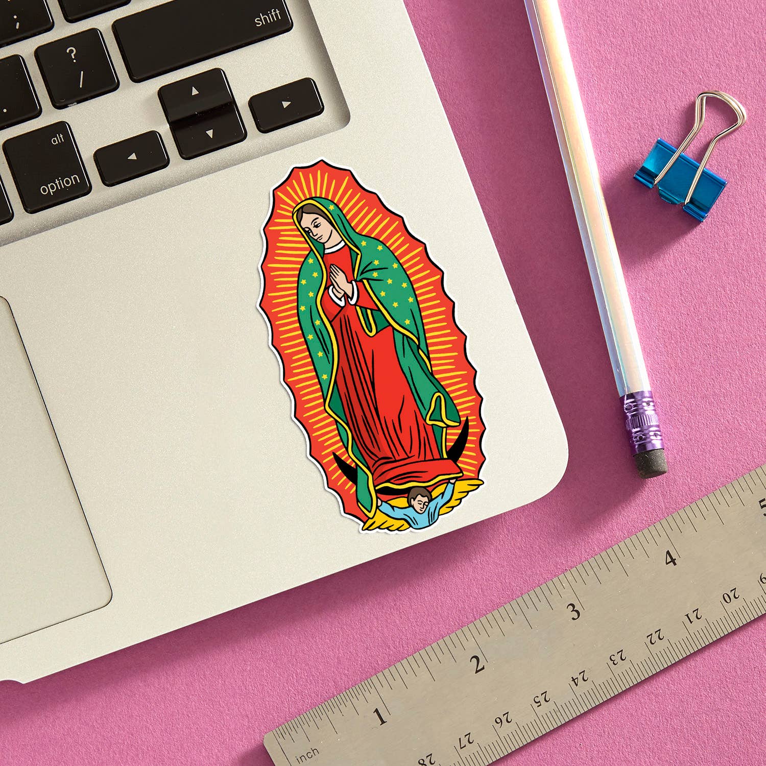 Virgin of Guadalupe die cut sticker displayed on silver laptop with pink background