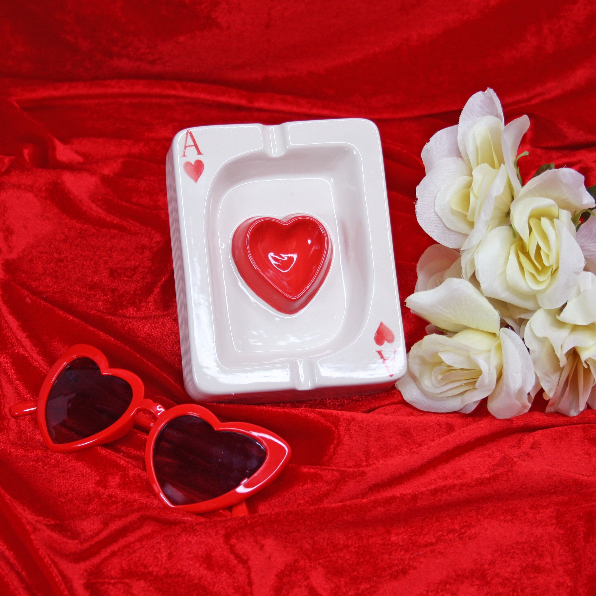 Clear acrylic Ace of Hearts playing card ashtray with red heart center on red fabric