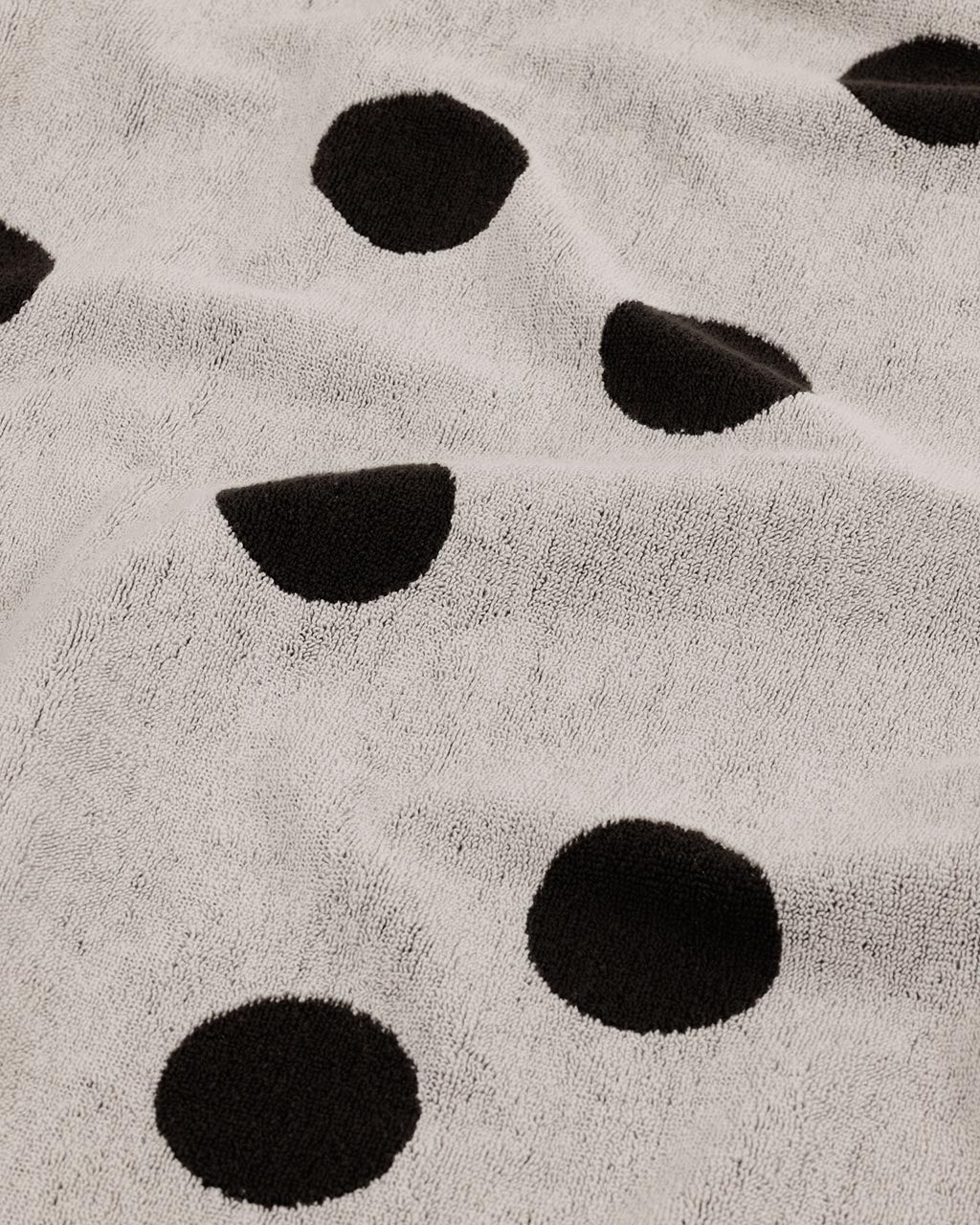 Close-up of cream terry cloth bath towel with large black polka dot pattern by Baggu