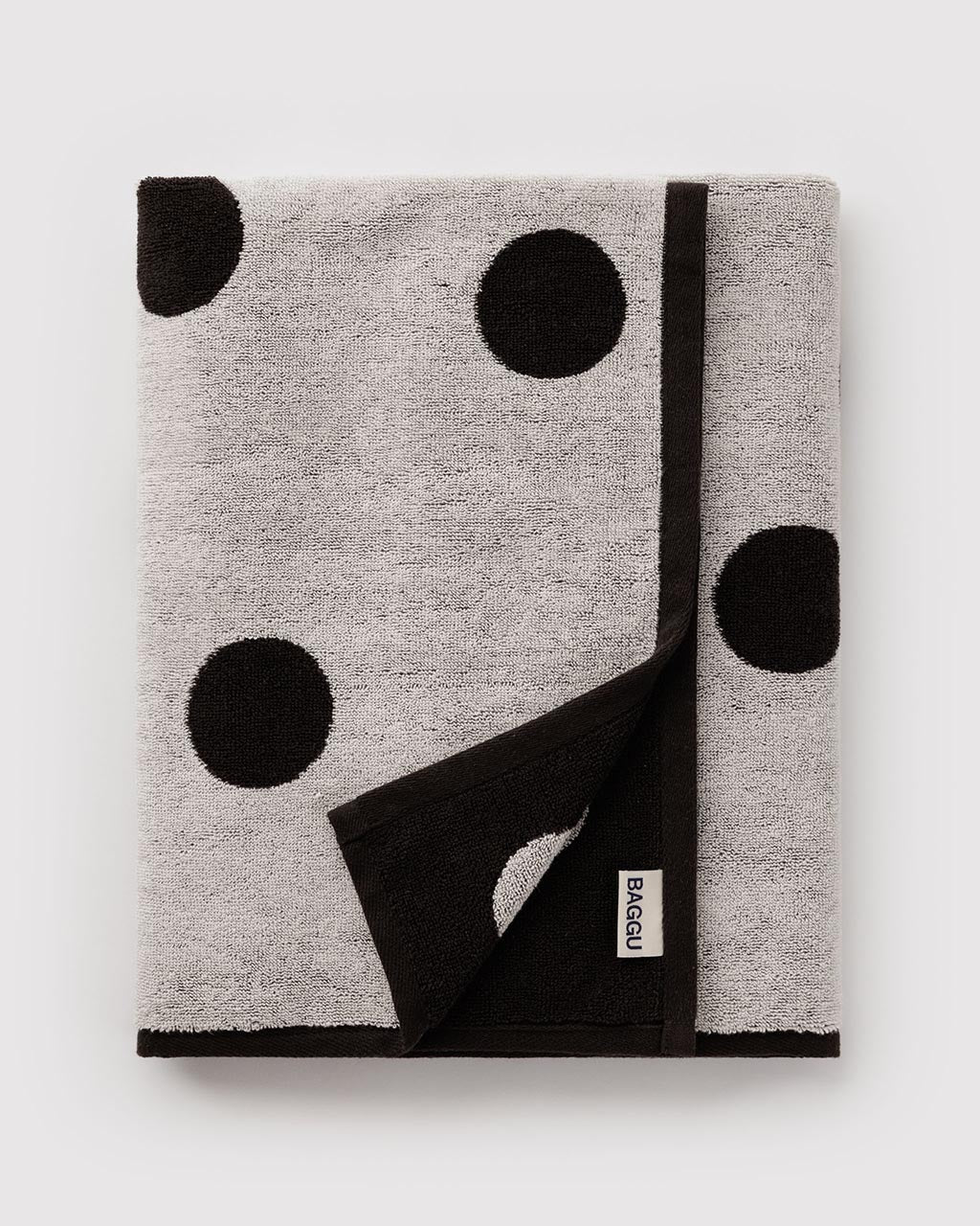 Folded Baggu bath towel in gray with large black polka dots and black border trim