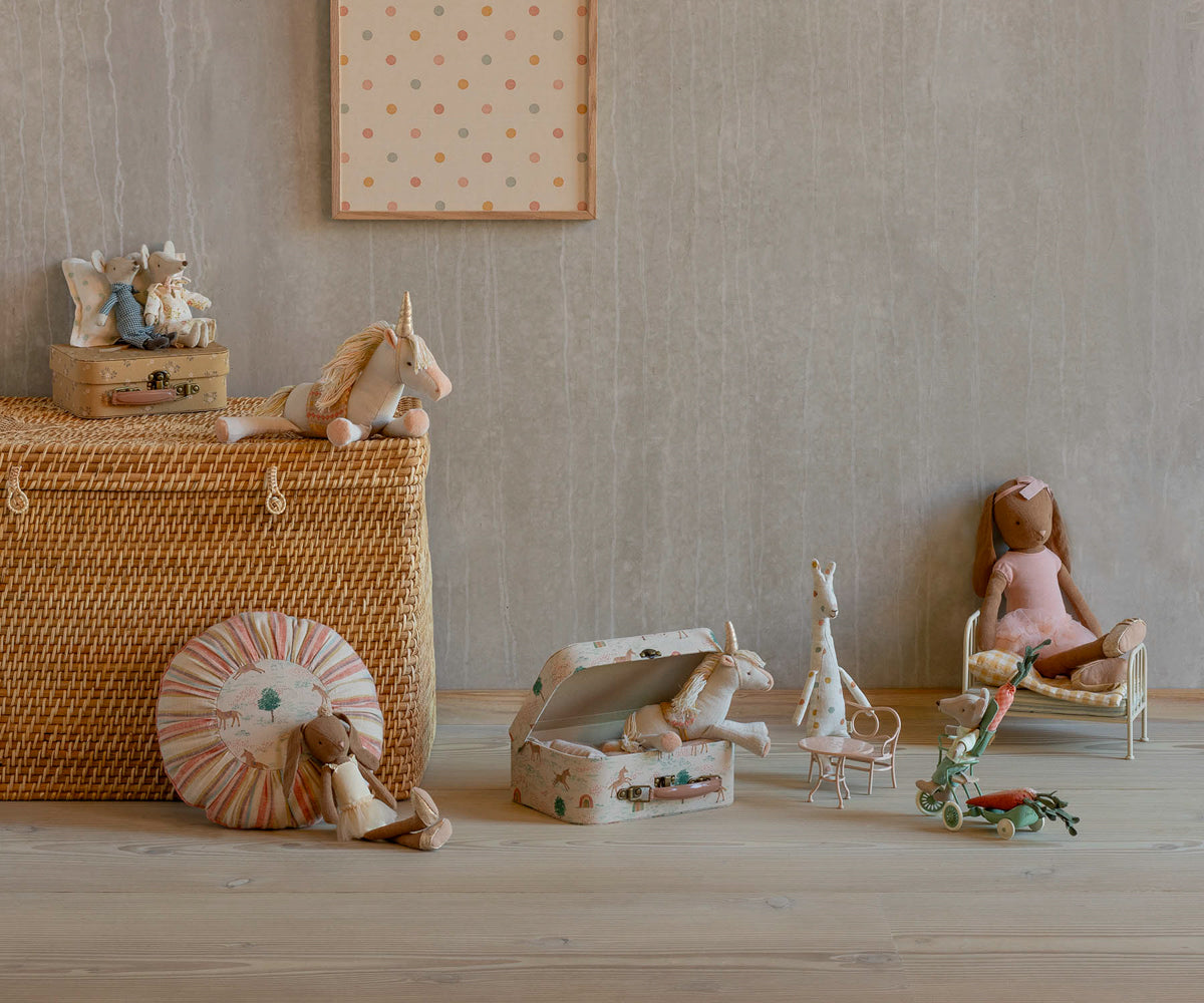 Maileg unicorn plush toy displayed in styled nursery setting with other toys and basket