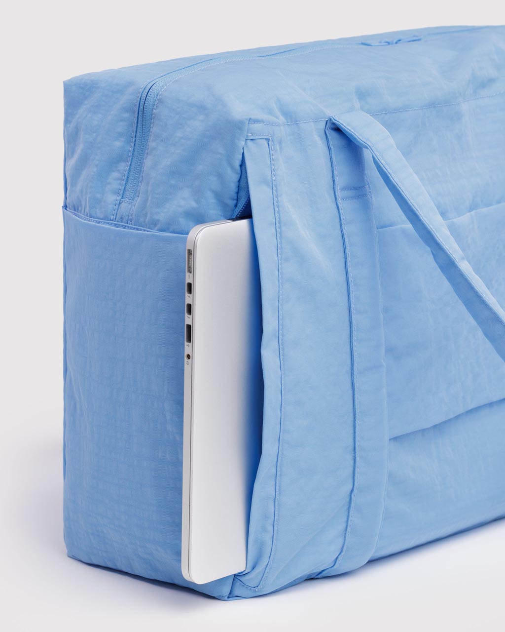 Light blue Baggu Cloud Carry-on bag with laptop tucked into exterior side pocket