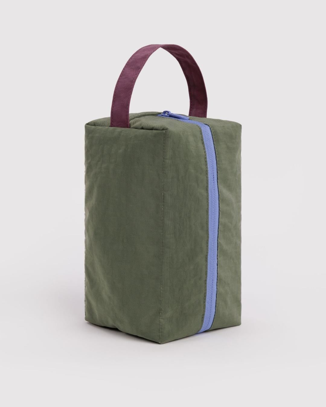 Olive green canvas dopp kit with blue zipper and burgundy carry handle on neutral background