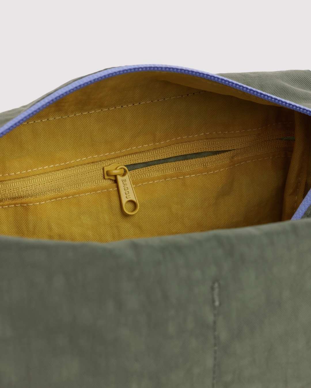 Interior view of Baggu Dopp Kit showing mustard yellow lining with branded zipper pocket