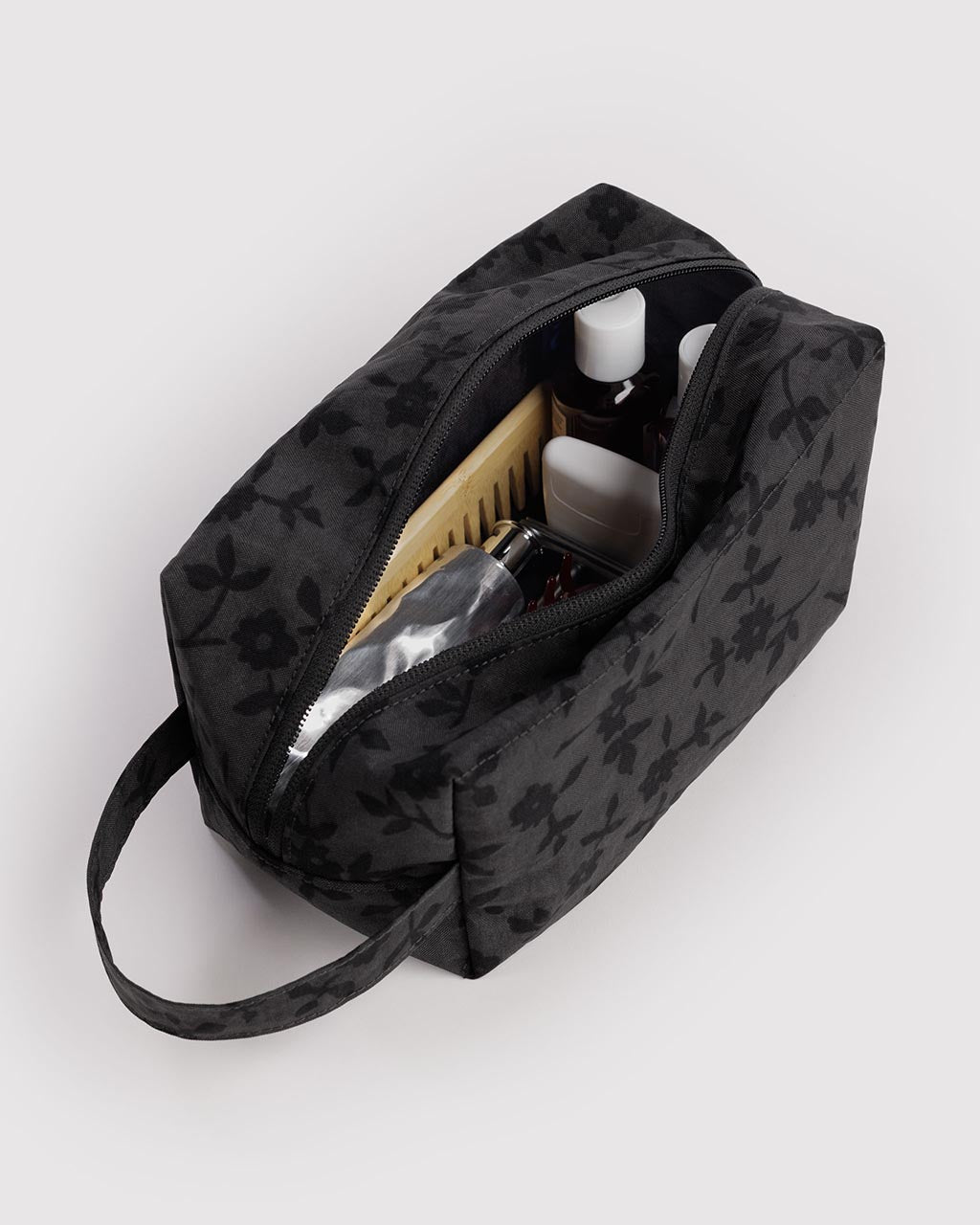 Open Baggu Dopp Kit in charcoal ditsy floral pattern filled with travel toiletries