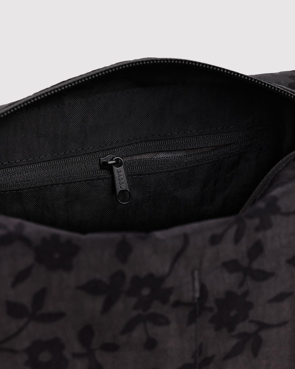 Interior view of Baggu Dopp Kit showing black lining, interior zipper pocket, and charcoal ditsy floral exterior fabric