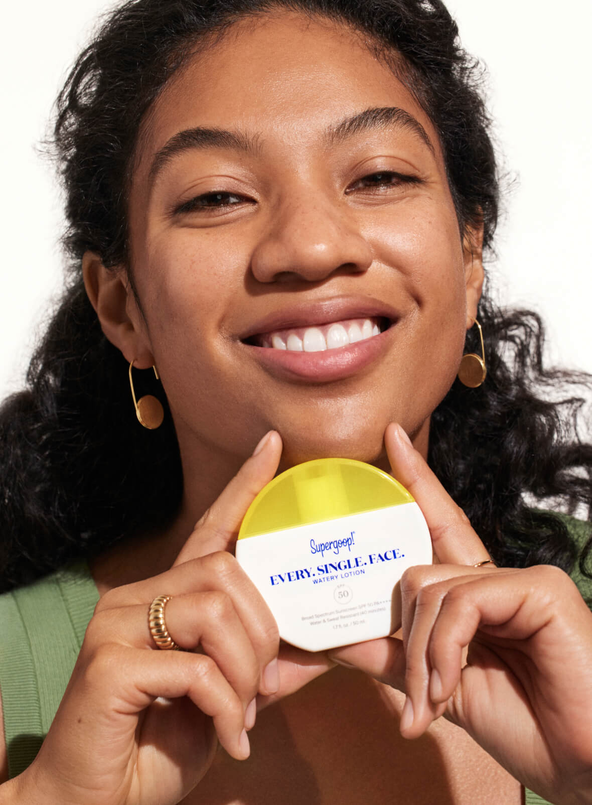 Smiling woman holding Supergoop Every Single Face Watery Lotion SPF 50 product container