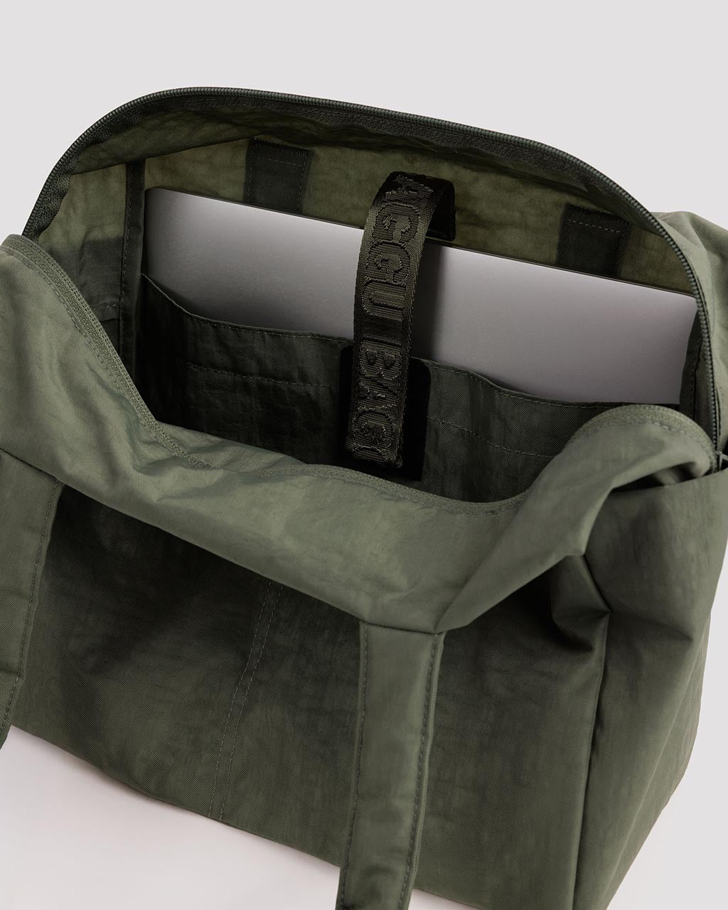 Open Baggu Everyday Cloud Bag in olive green showing interior laptop compartment and organization pockets