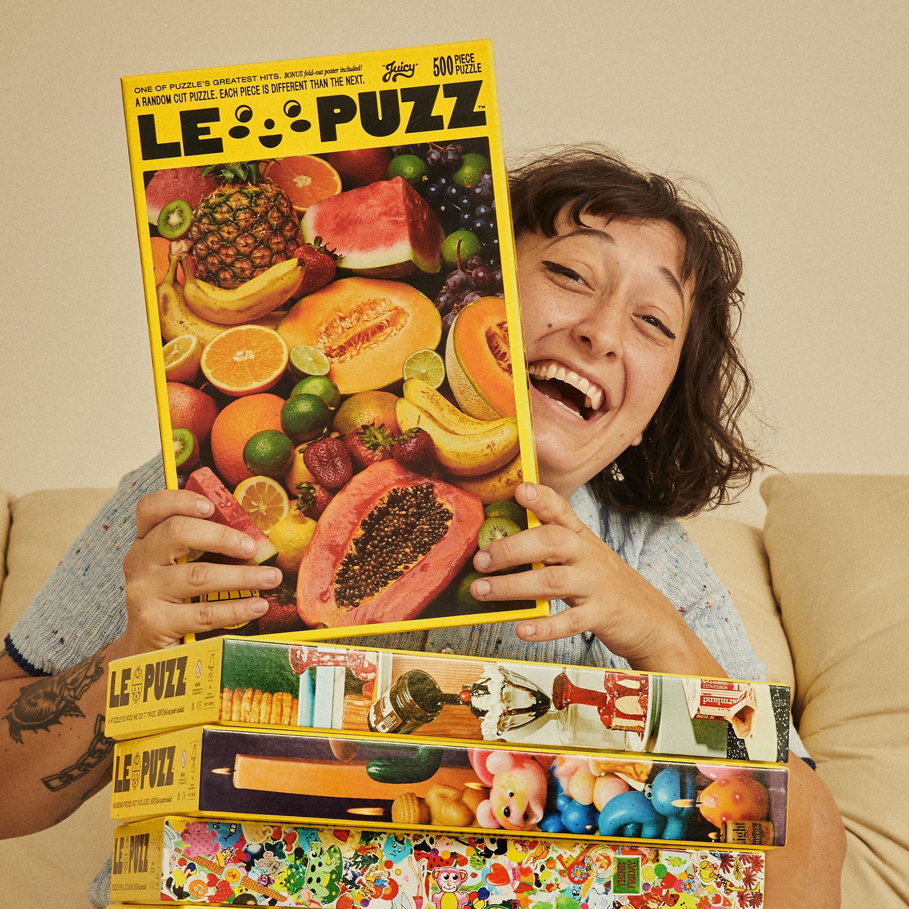 Smiling woman holding Le Puzz Juicy 500-piece puzzle box featuring vibrant assorted tropical fruits