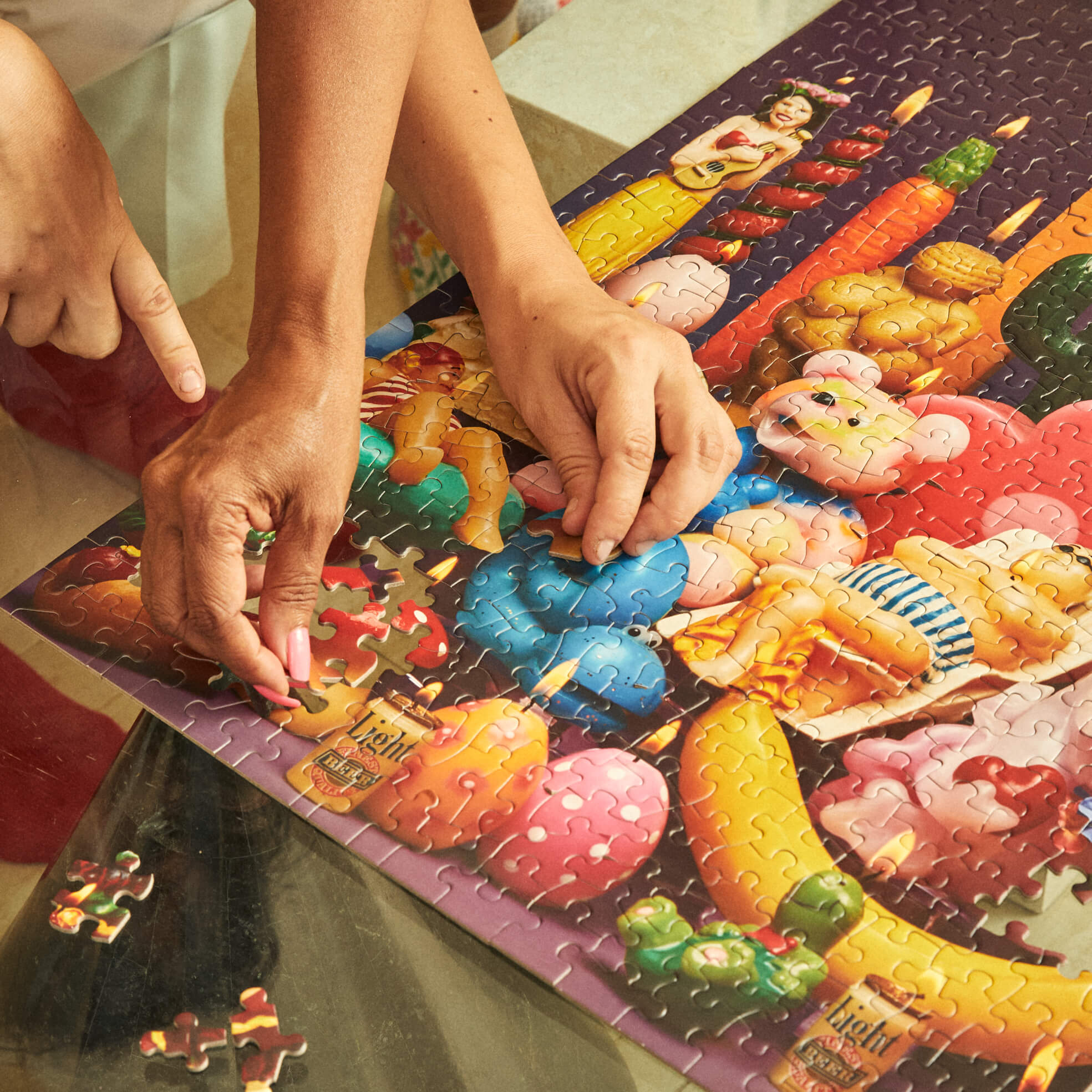 Person assembling the colorful Le Puzz 'Lighten Up' jigsaw puzzle featuring candy and toys