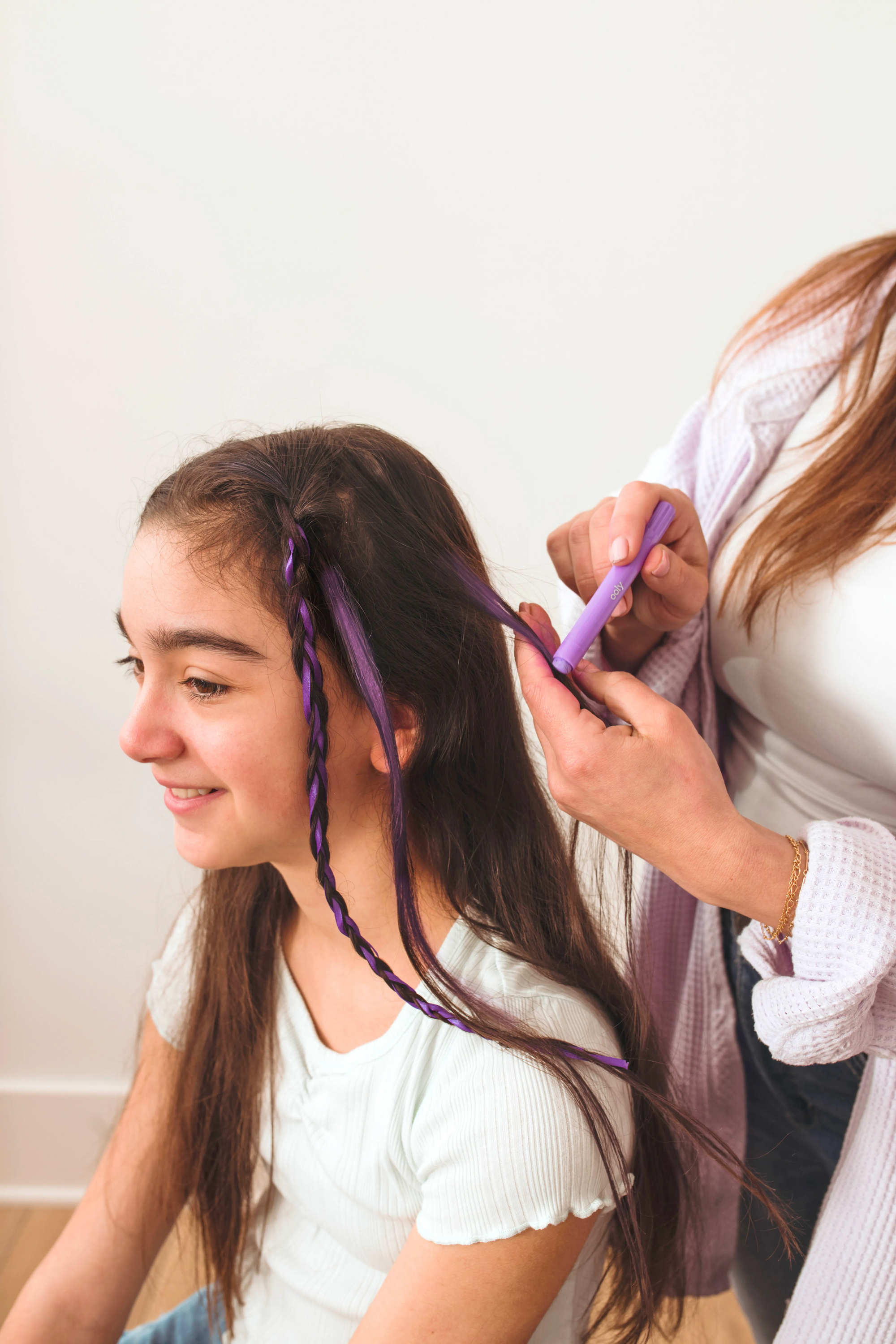 Person applying purple hair chalk crayon to create temporary colored streaks in brown hair