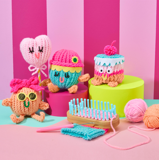 Colorful knitted toys and knitting tools on a pink and green striped background