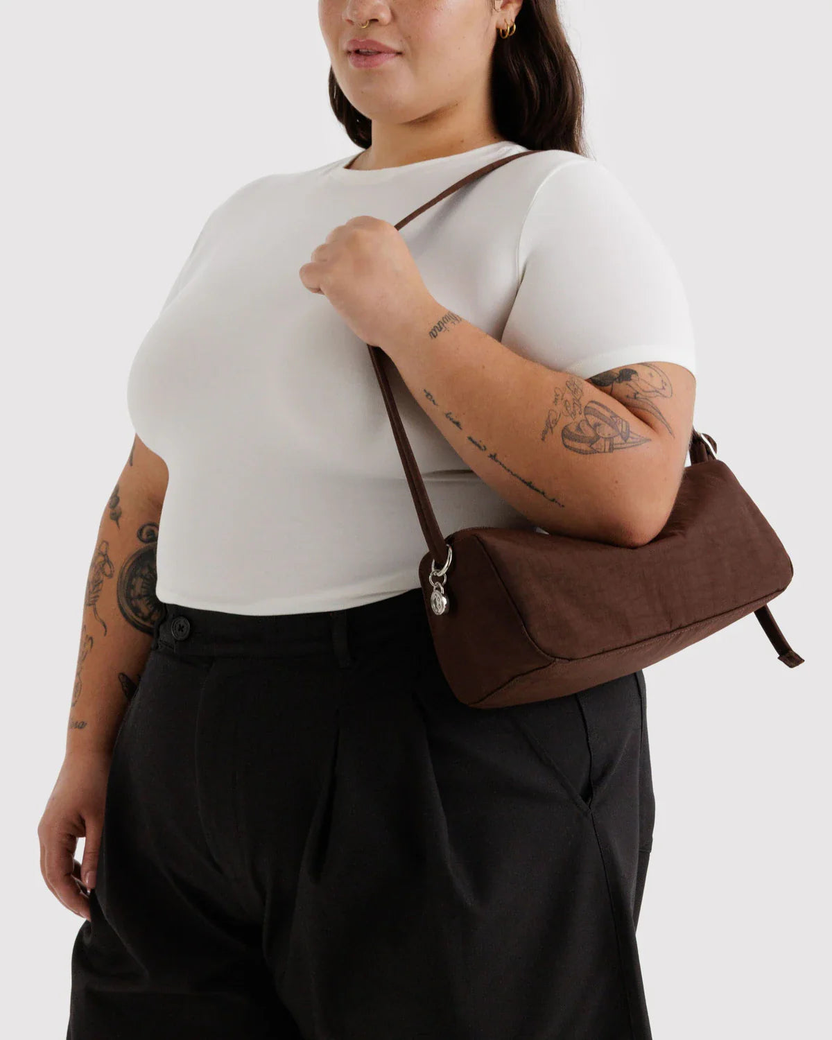 Model carrying a dark brown nylon loaf shoulder bag against a neutral background