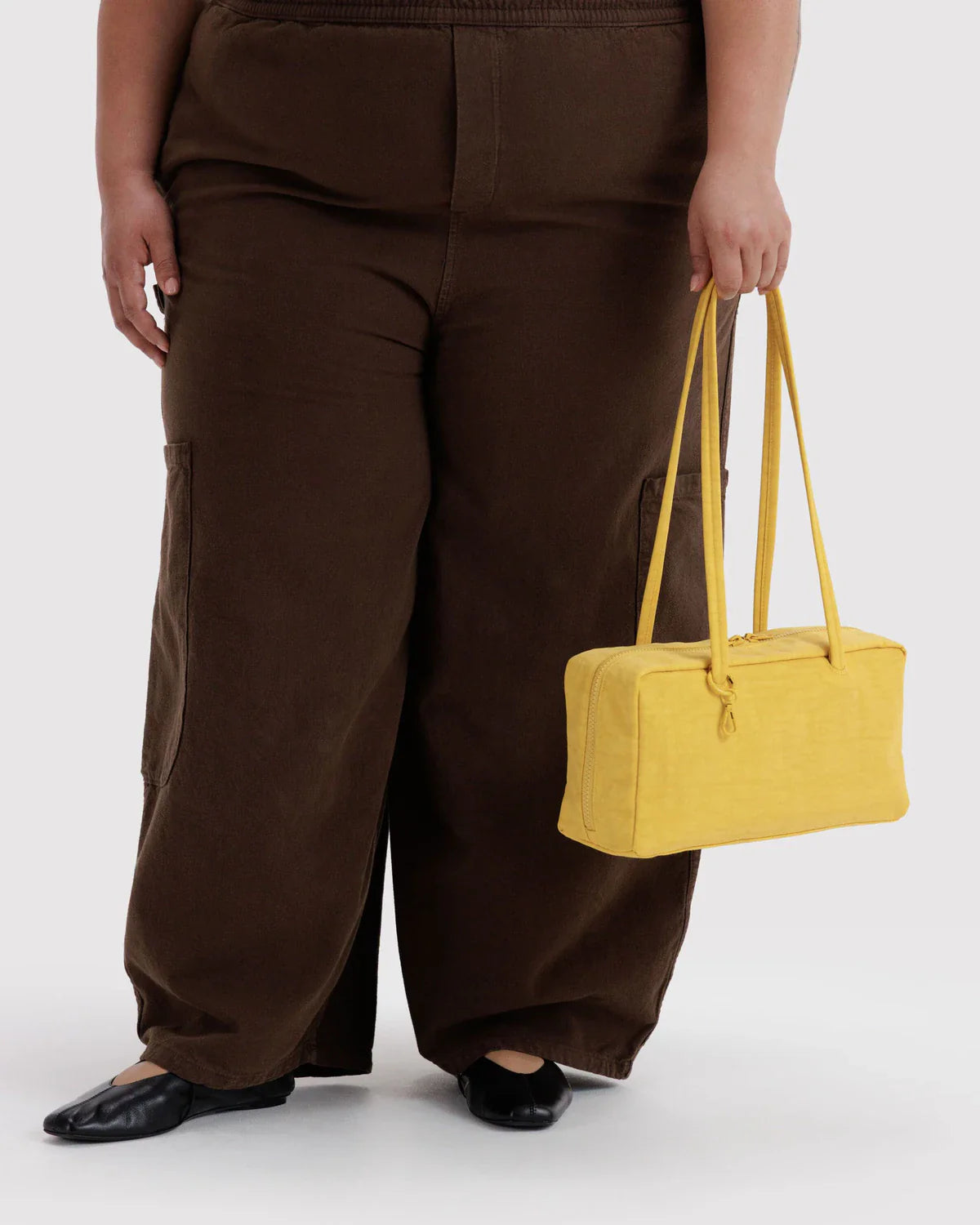 Model holding a yellow nylon bowler bag with double handles against neutral background
