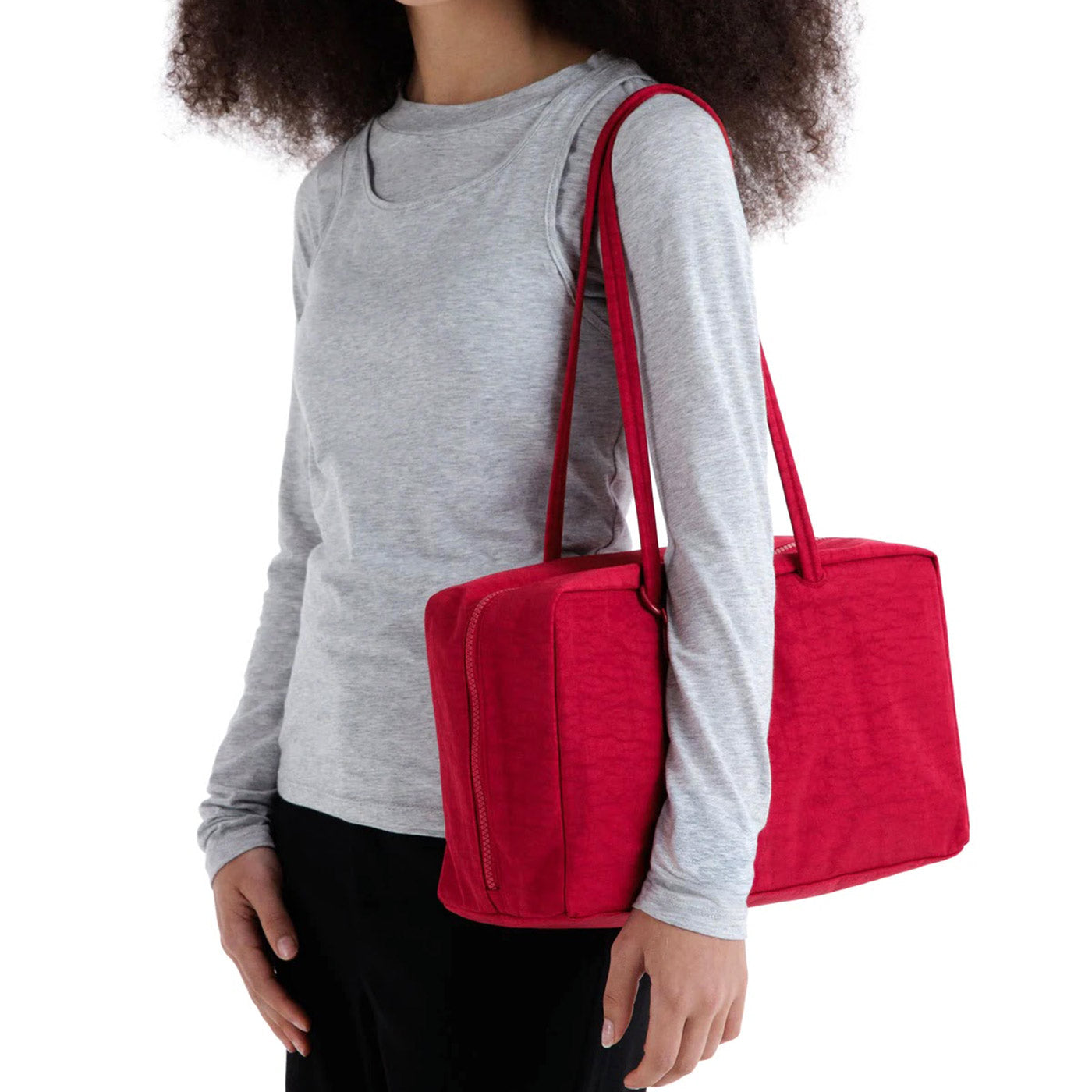 Model wearing cherry red Baggu Medium Nylon Bowler Bag on shoulder against white background