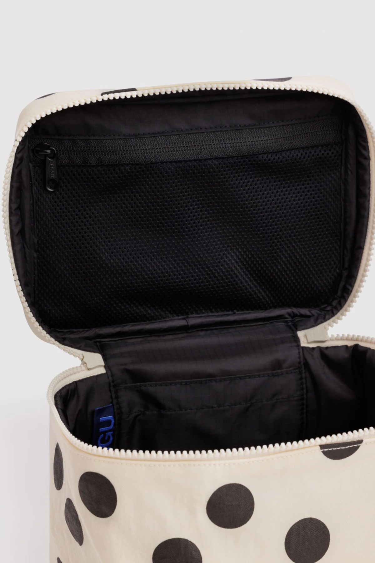 Open Baggu large cosmetic case in cream with black polka dots showing black interior mesh pocket