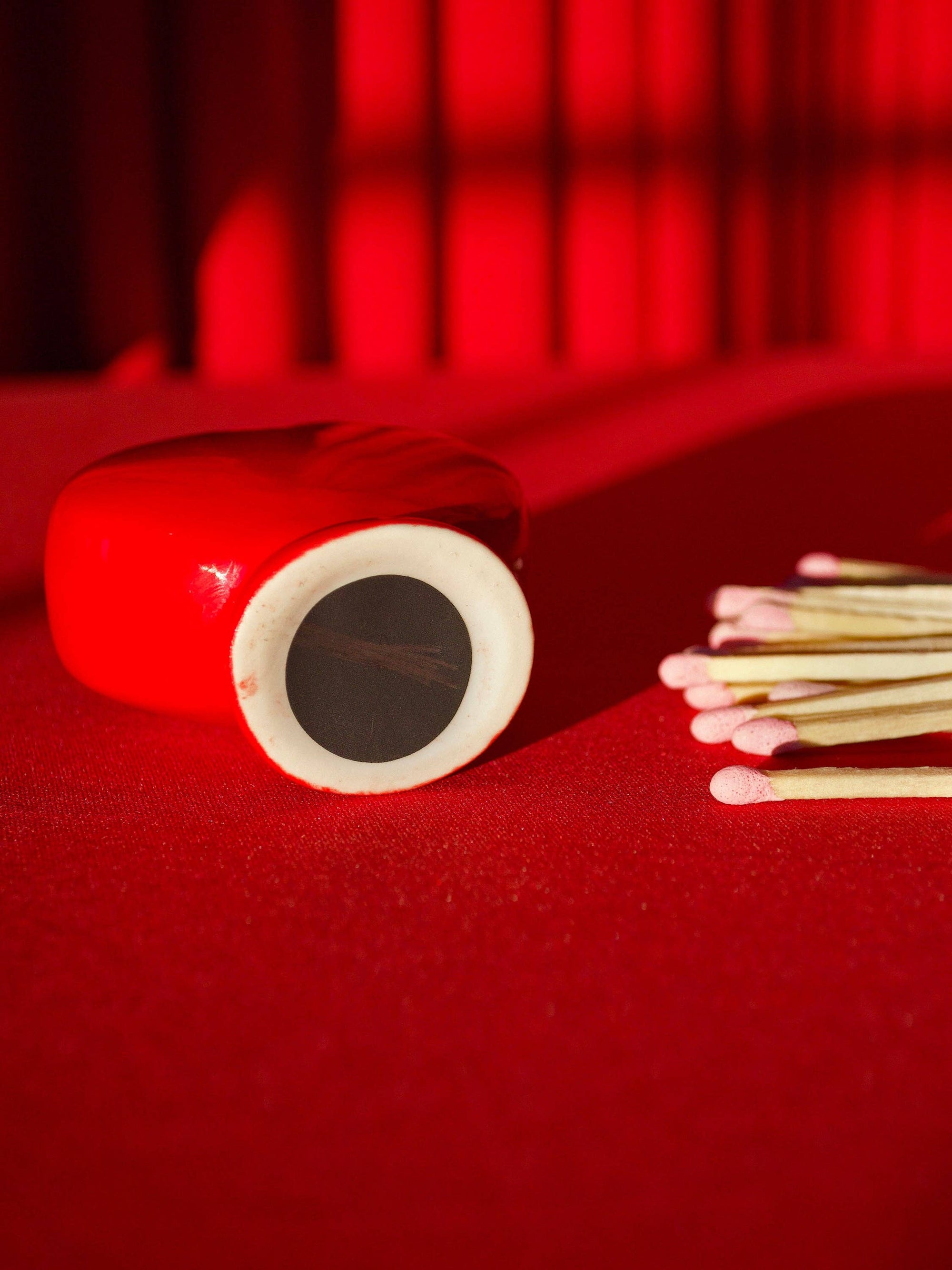 Red heart-shaped match striker with white interior and matchsticks on red surface