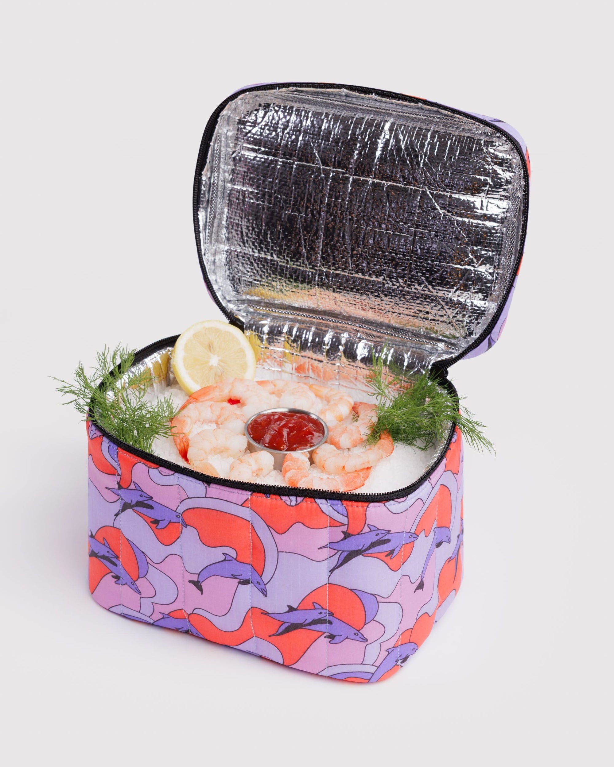 Open Baggu Puffy Lunch Bag in dolphin print filled with shrimp cocktail on ice