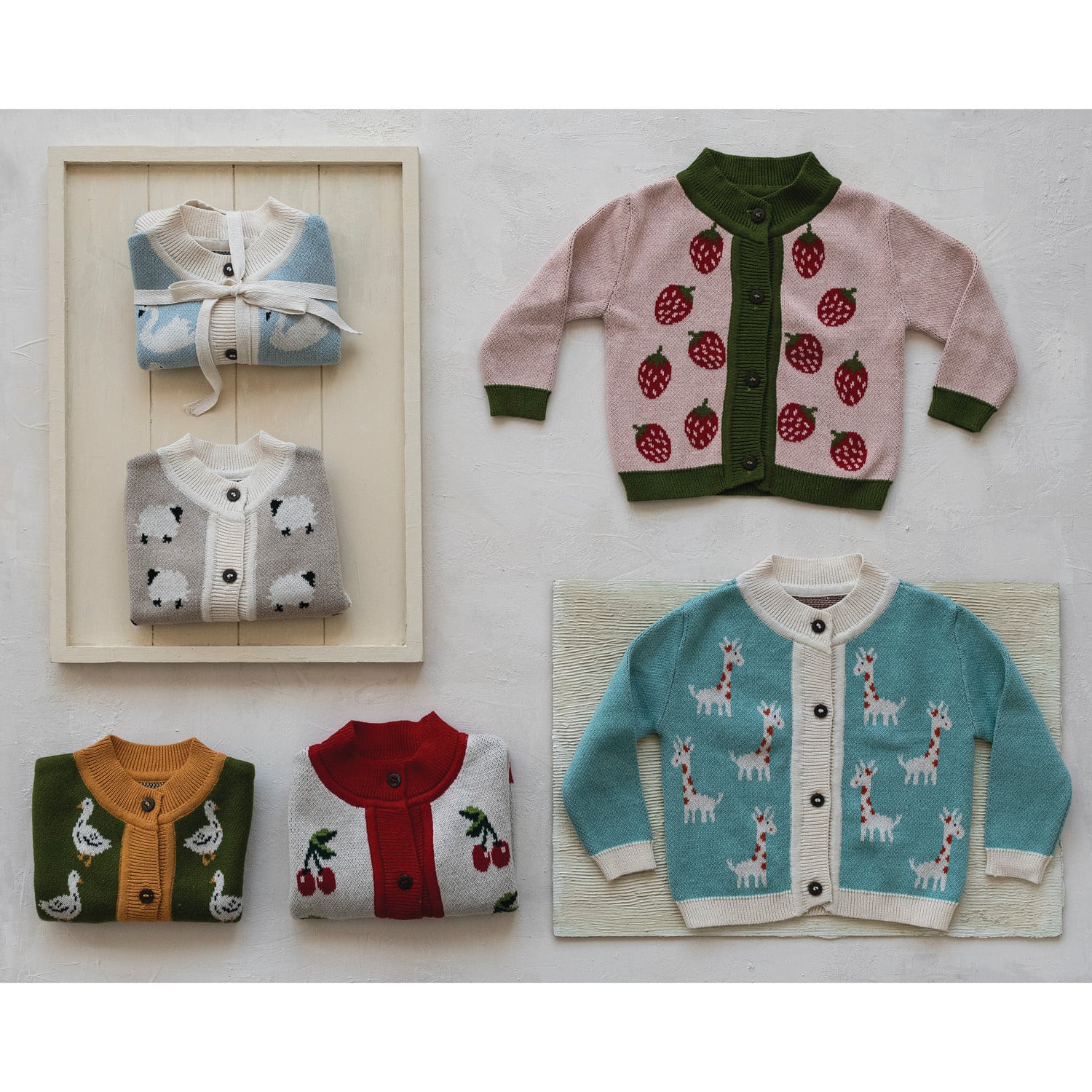 Pink knit baby cardigan sweater with red strawberry pattern and green trim buttons
