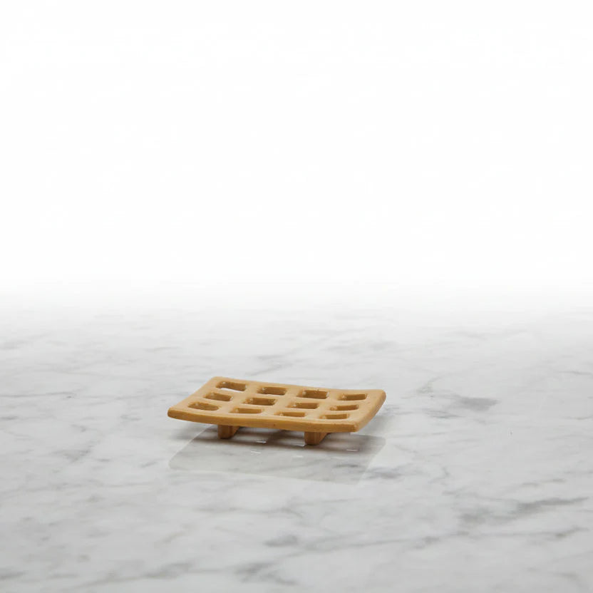 Natural beige stoneware soap dish with grid pattern and feet on marble surface