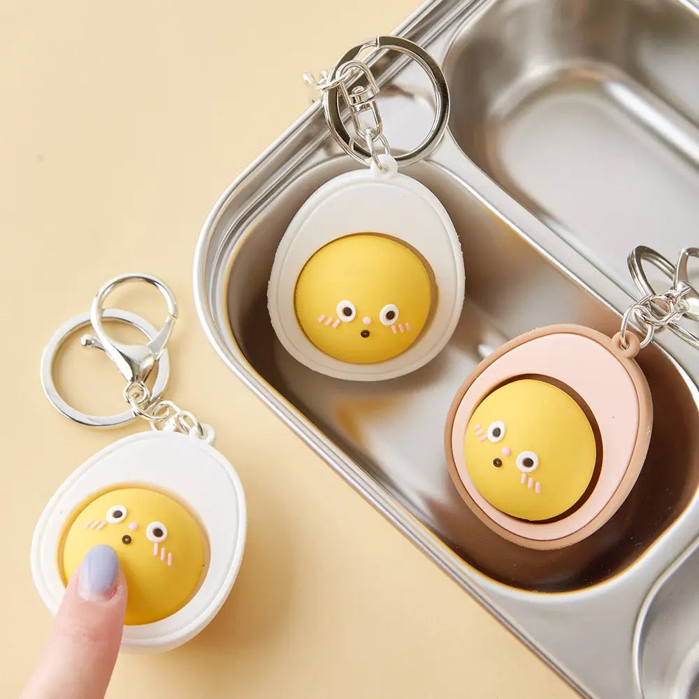 Cute boiled egg keychain with yellow yolk face and squishy clicker center in white and pink versions