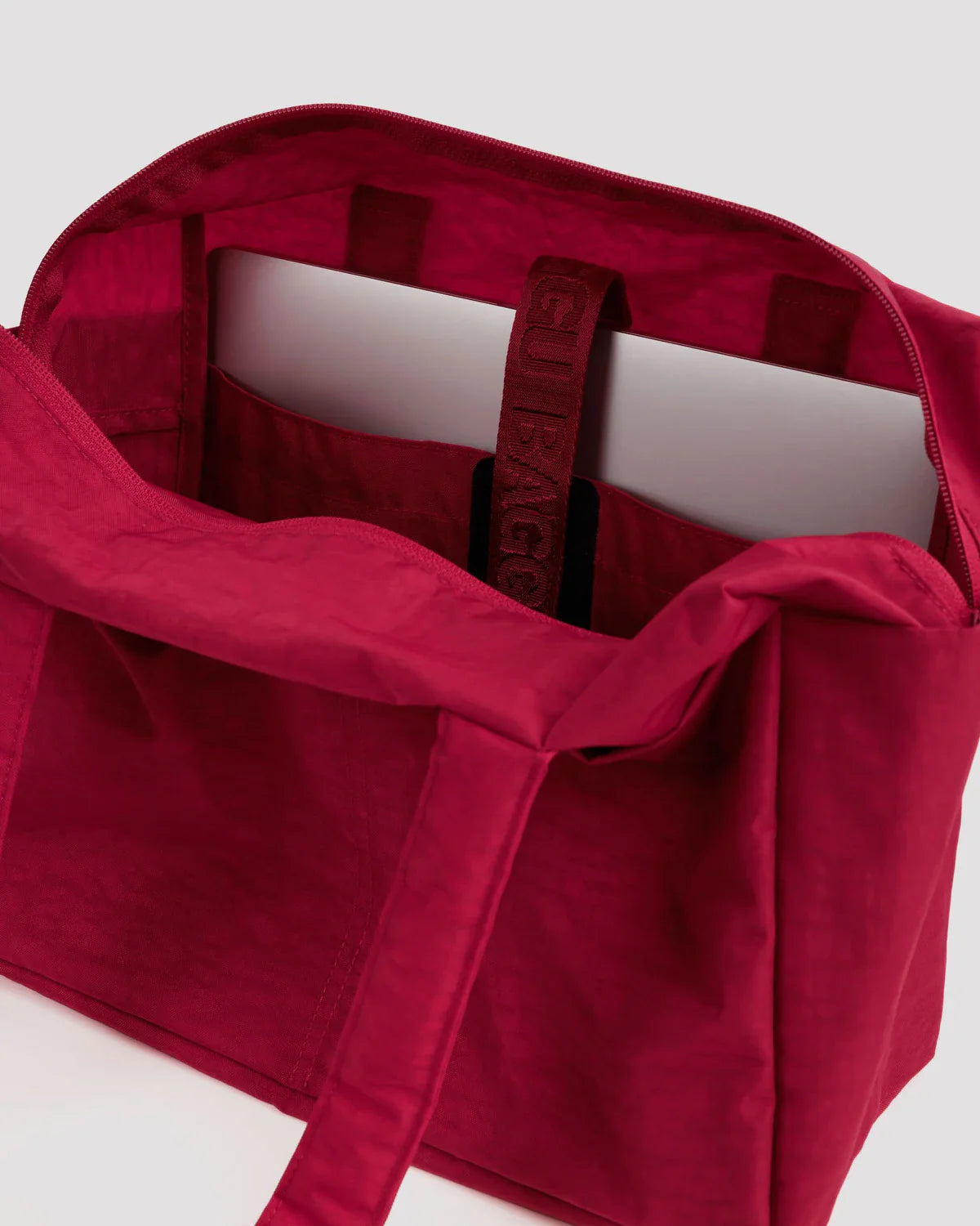 Open cherry red Baggu Everyday Cloud Bag showing interior laptop sleeve and spacious compartment