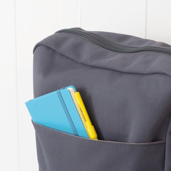 LEUCHTTURM1917 turquoise A6 pocket notebook and yellow pen in gray backpack front pocket