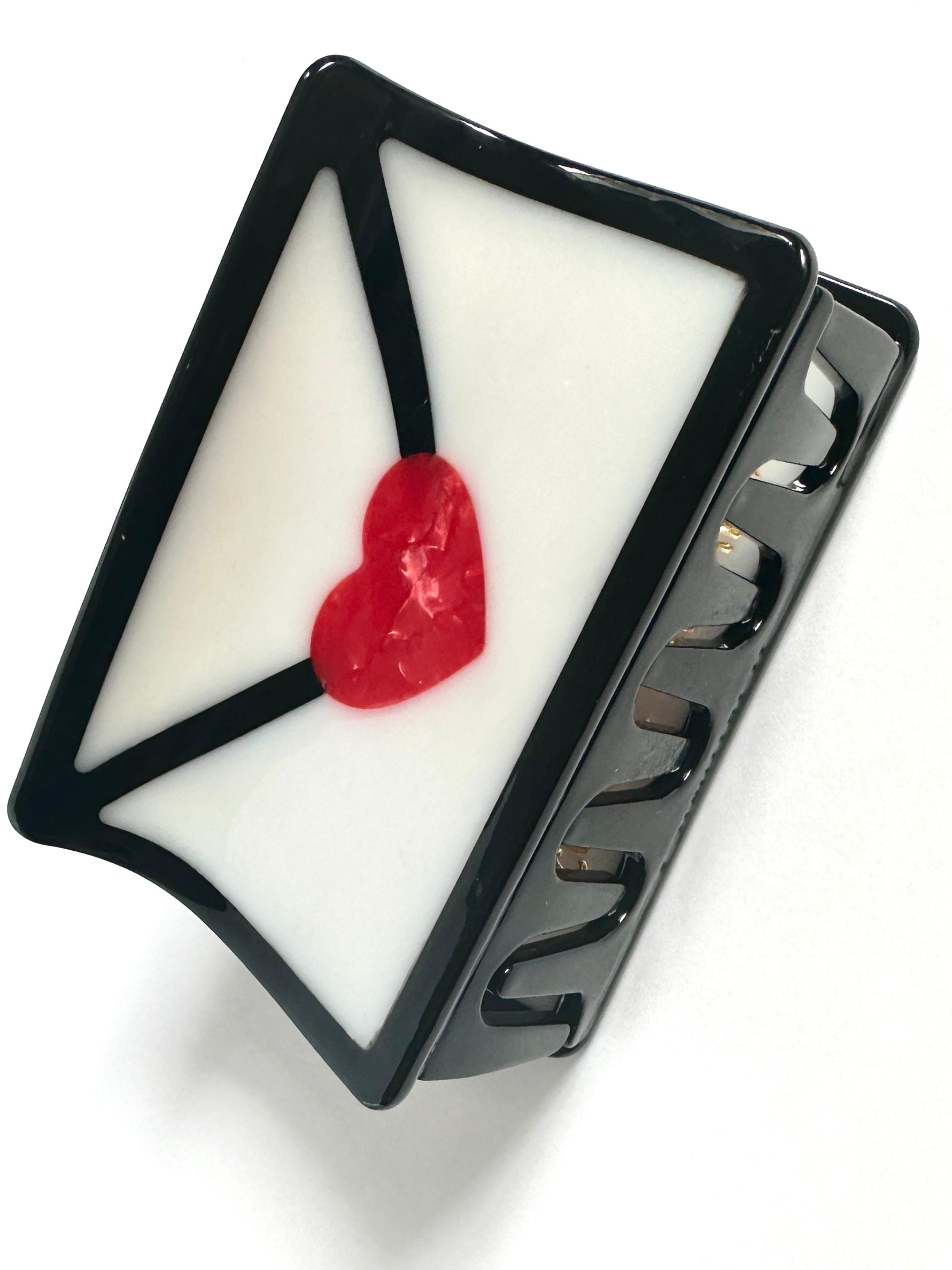 Black triangular hair claw with white envelope design and red heart detail
