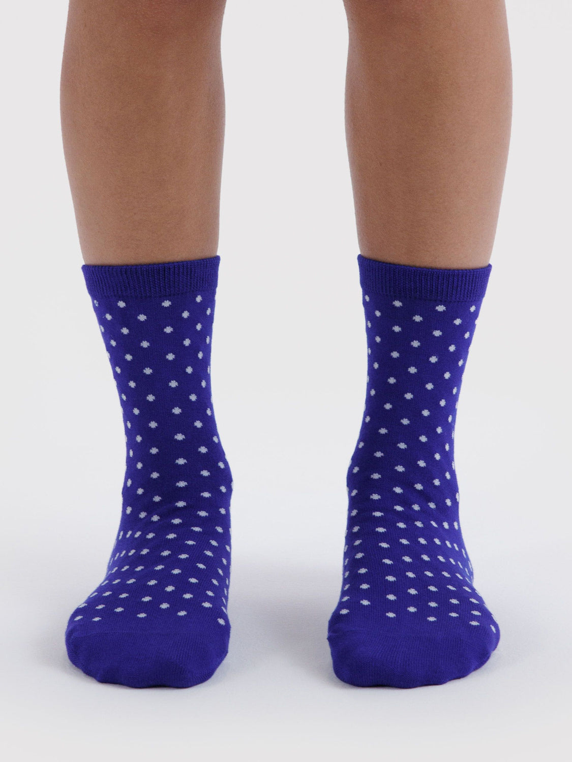 Model wearing blue crew socks with white micro polka dot pattern on neutral background