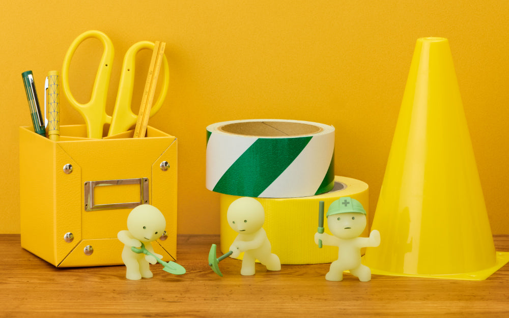 Three glow-in-the-dark SMISKI construction minifigures posed with yellow office supplies and tape rolls